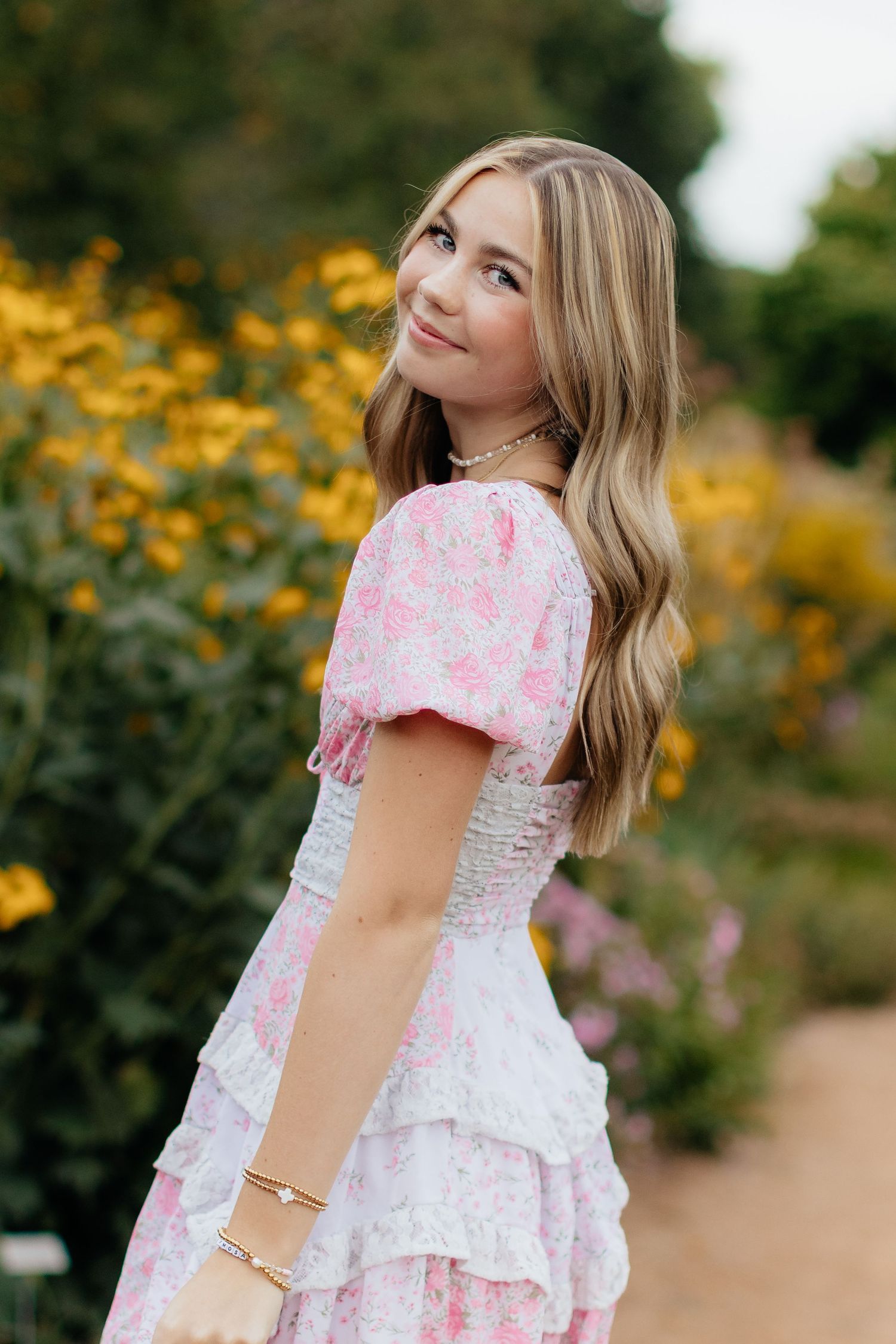Garden portraits in pink and white floral dress with yellow flowers.