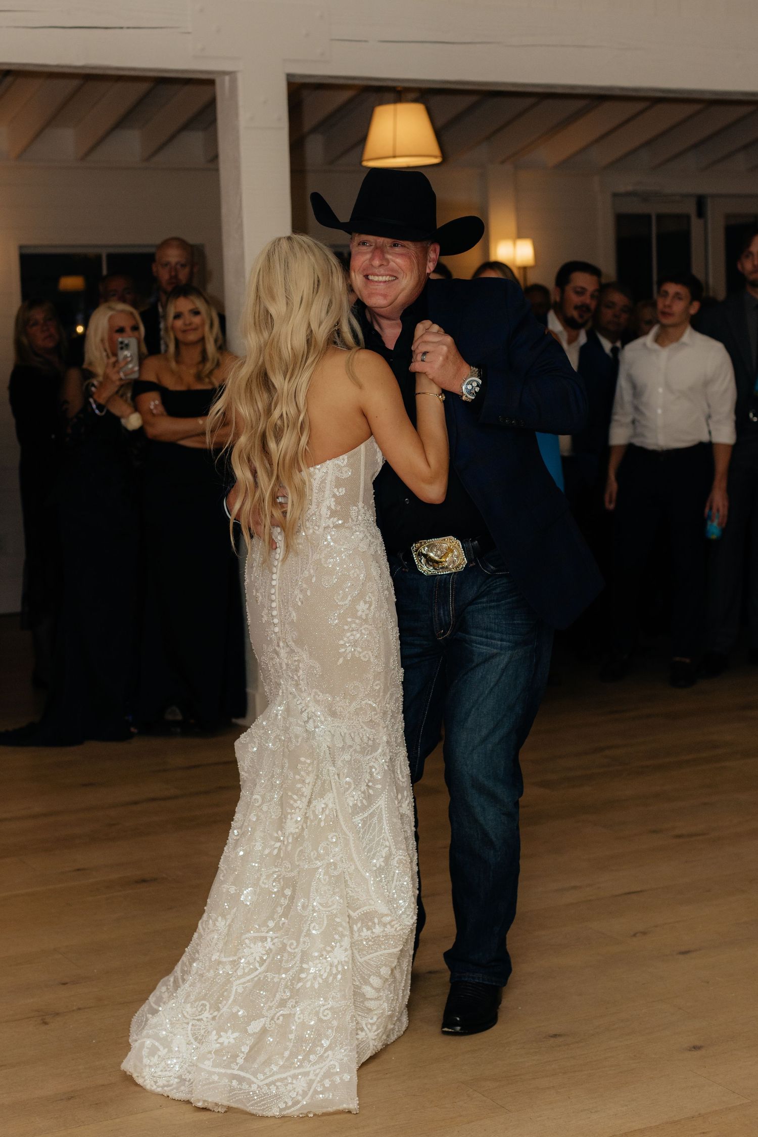 Wedding couple dancing together on a wooden floor during their reception celebration.