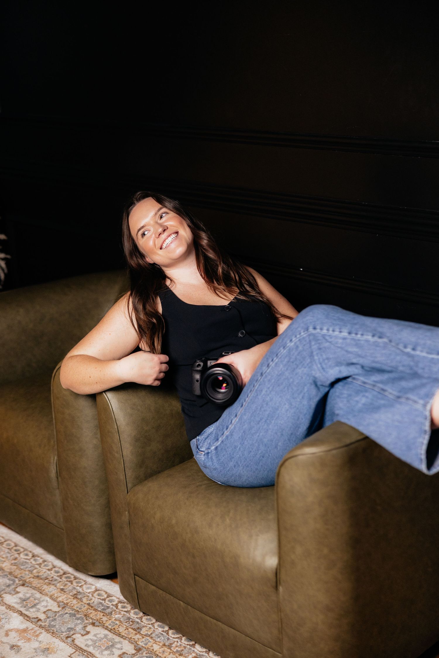Creative photography session on brown leather sofa with dramatic lighting.
