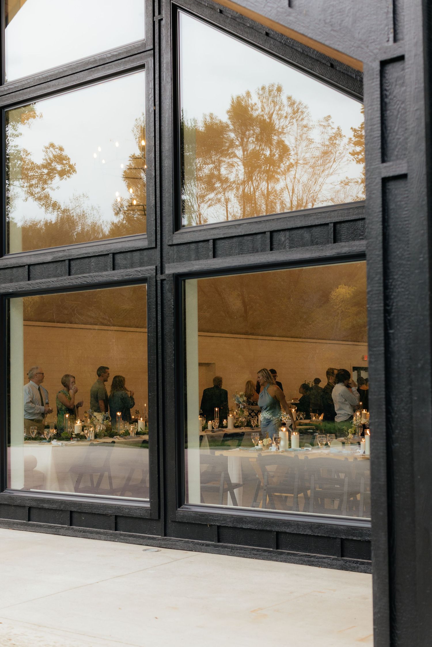 Wedding reception venue viewed through large geometric windows at dusk.