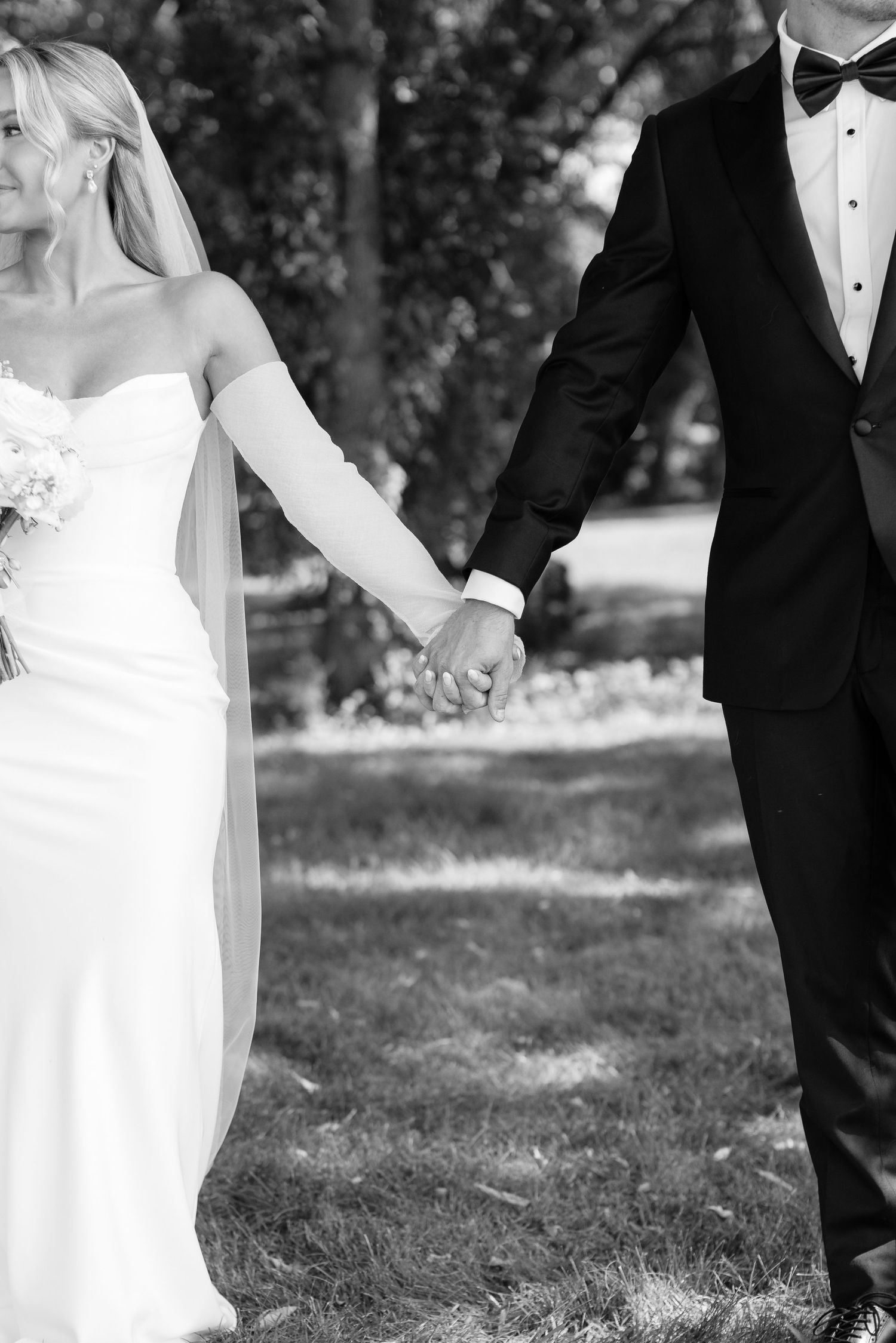 Black and white wedding portrait showing couple in elegant attire during outdoor ceremony.