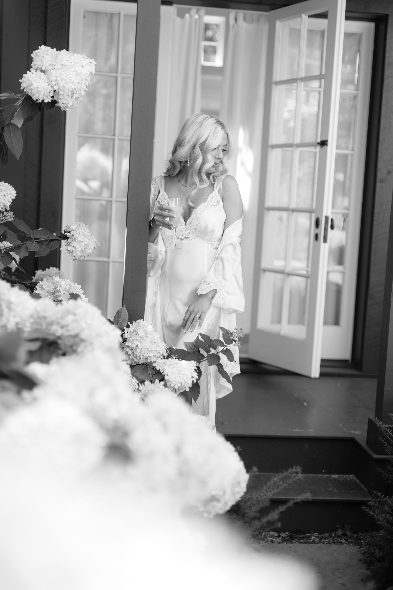 Black and white photo of a sunlit porch with blooming hydrangeas.