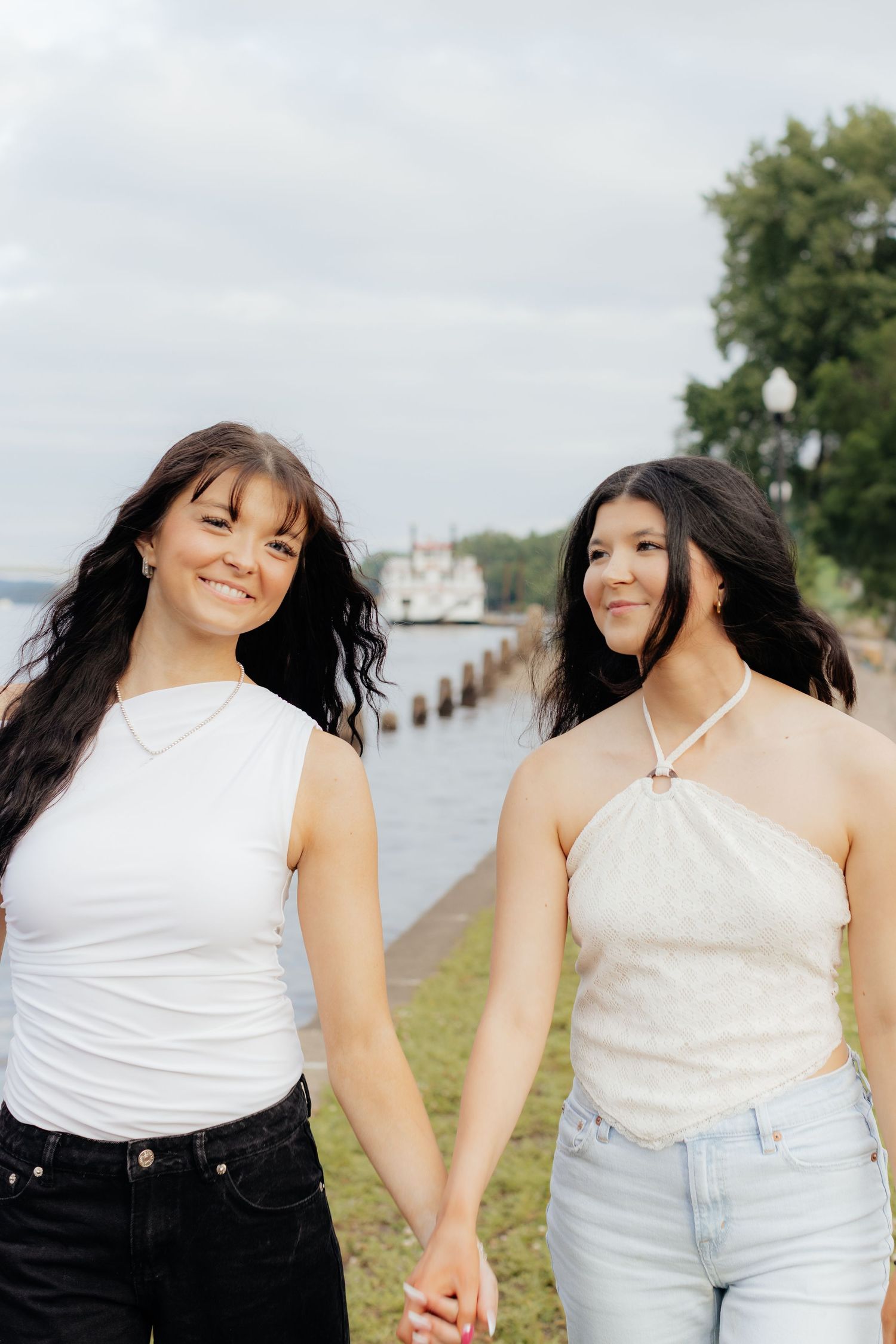 Friends pose together by the waterfront wearing coordinated white and denim outfits.