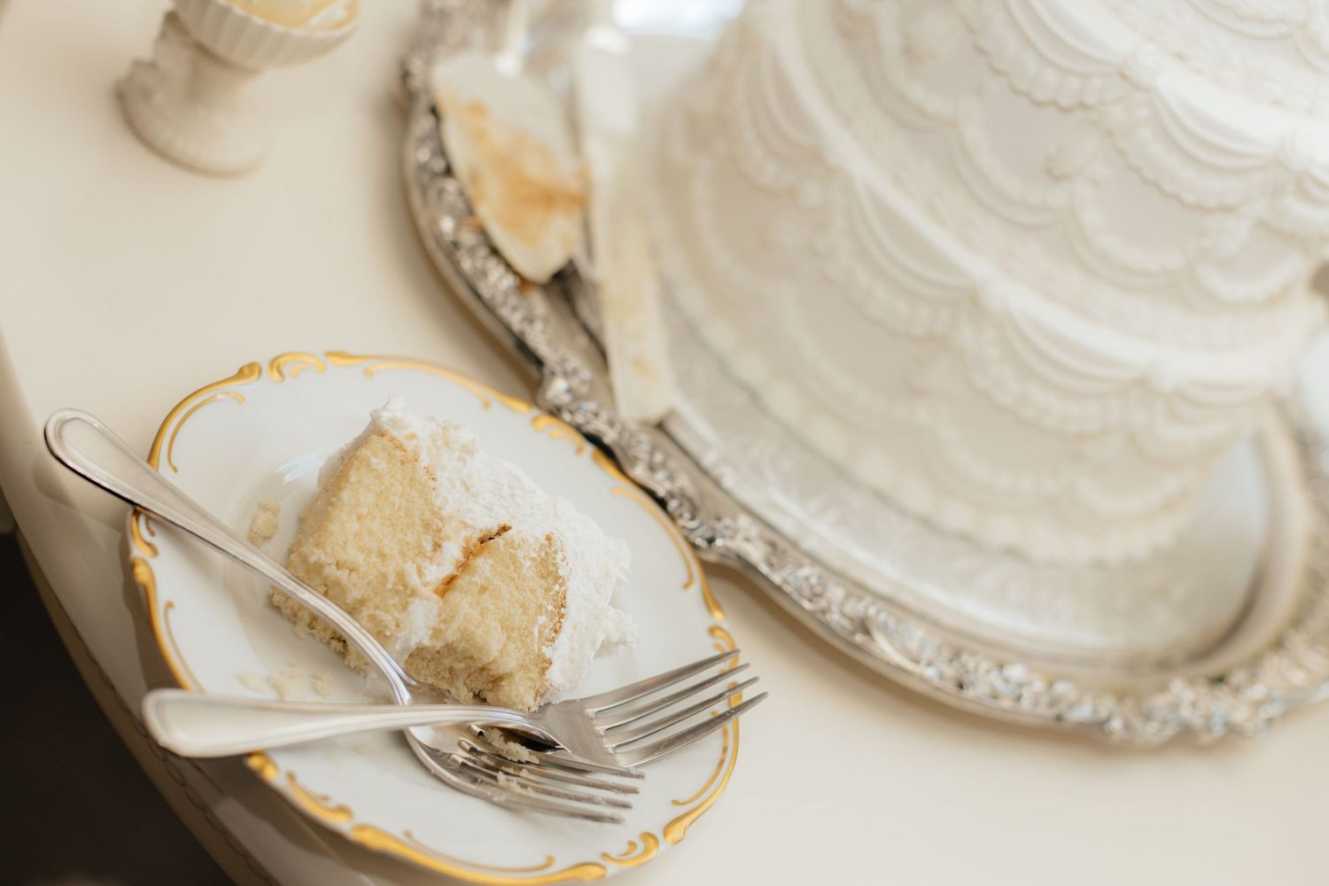 Slices of white wedding cake served on ornate china plates.