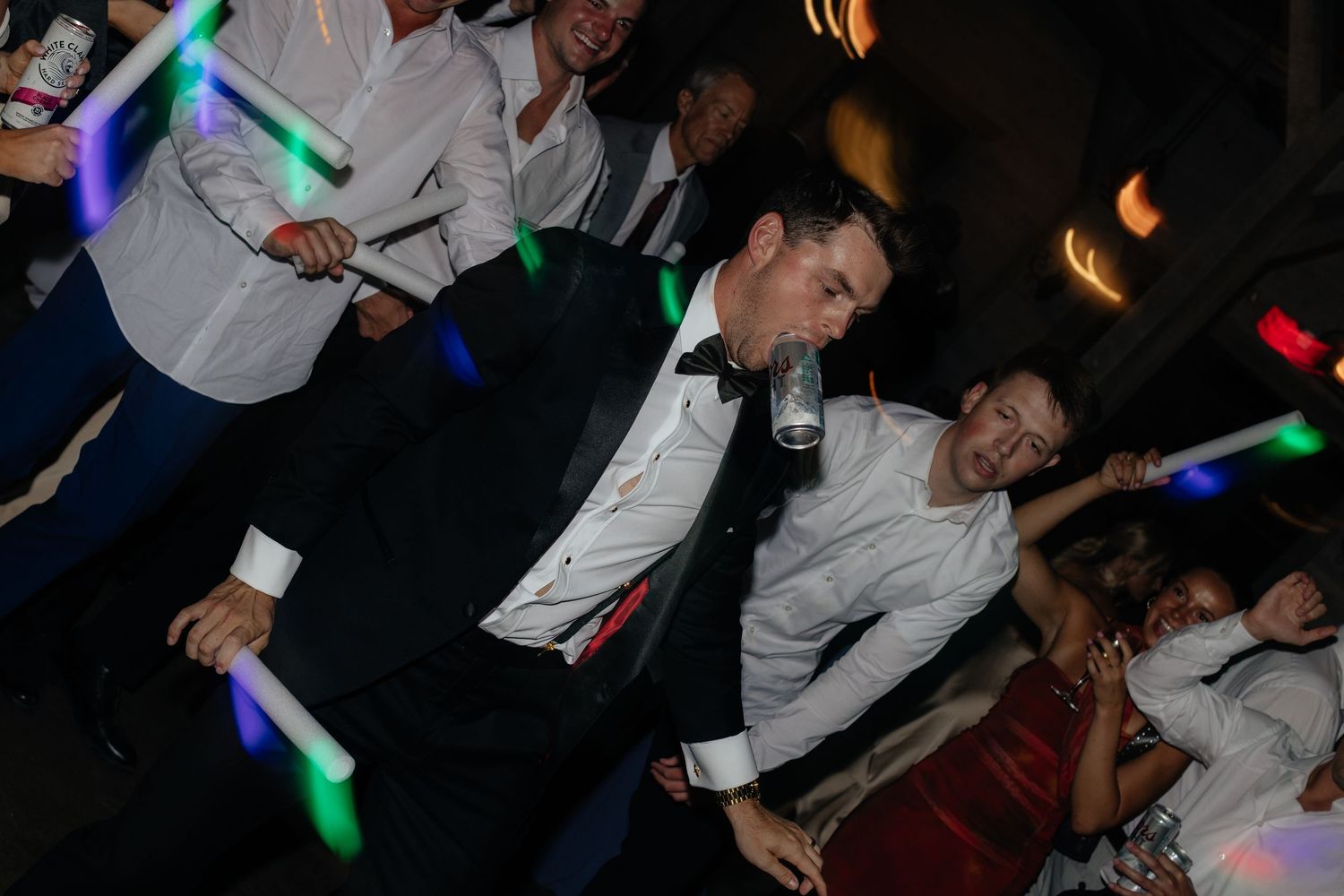 Wedding reception dance party with colorful glow sticks and celebration on the dance floor.