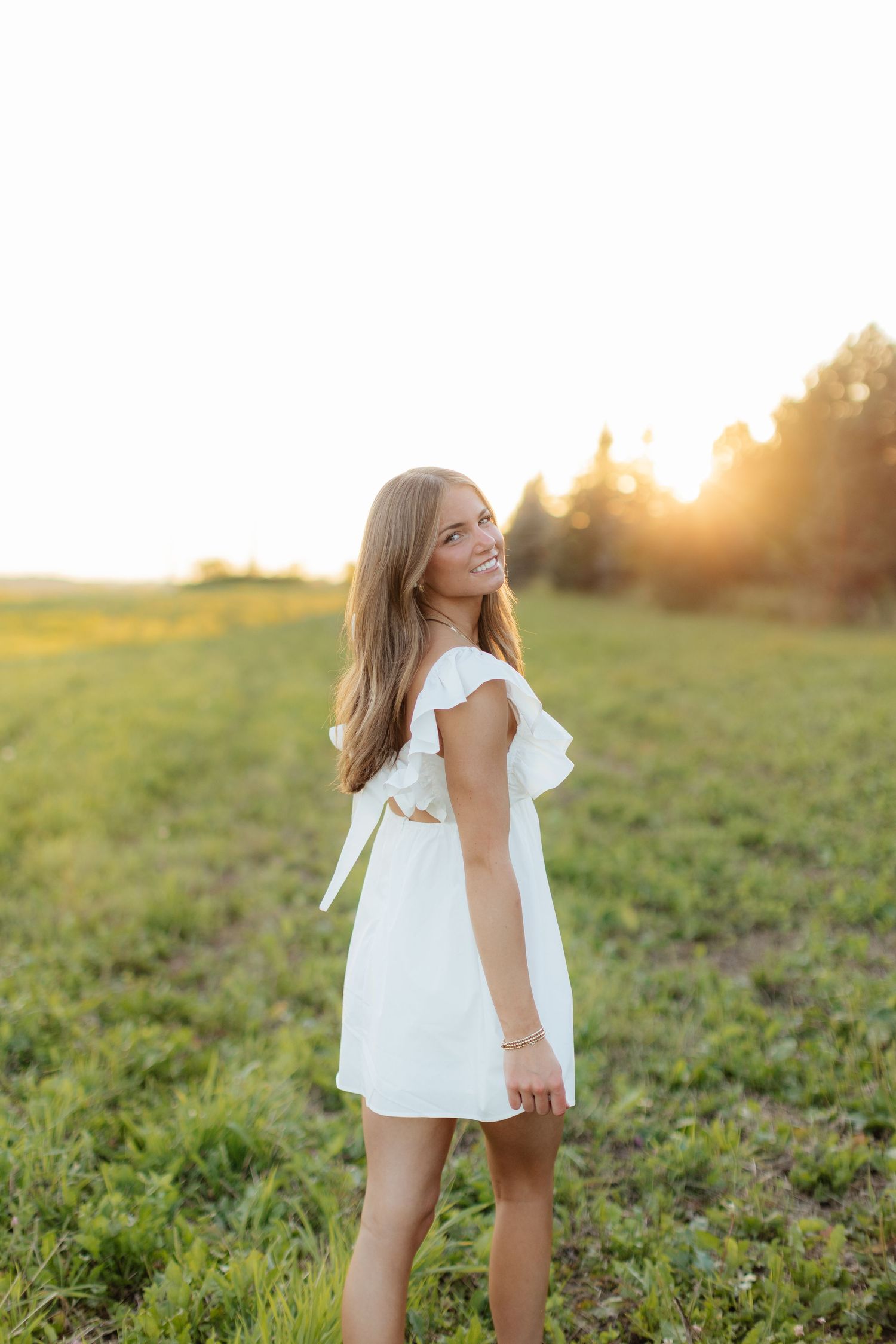 Whimsical outdoor photoshoot in white dress during golden hour.