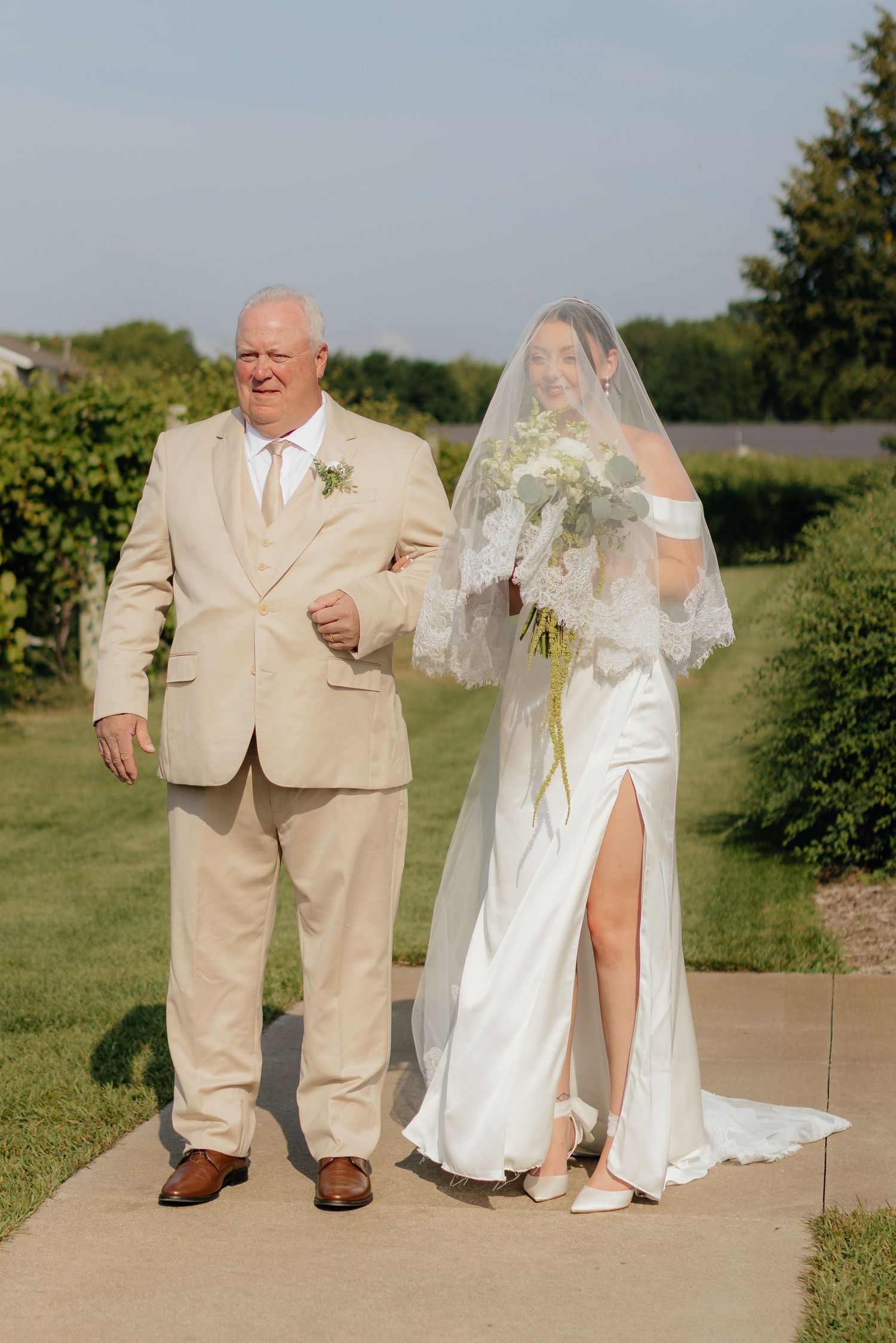 Wedding couple takes creative first look photos outdoors in formal attire with tan suit and white dress.