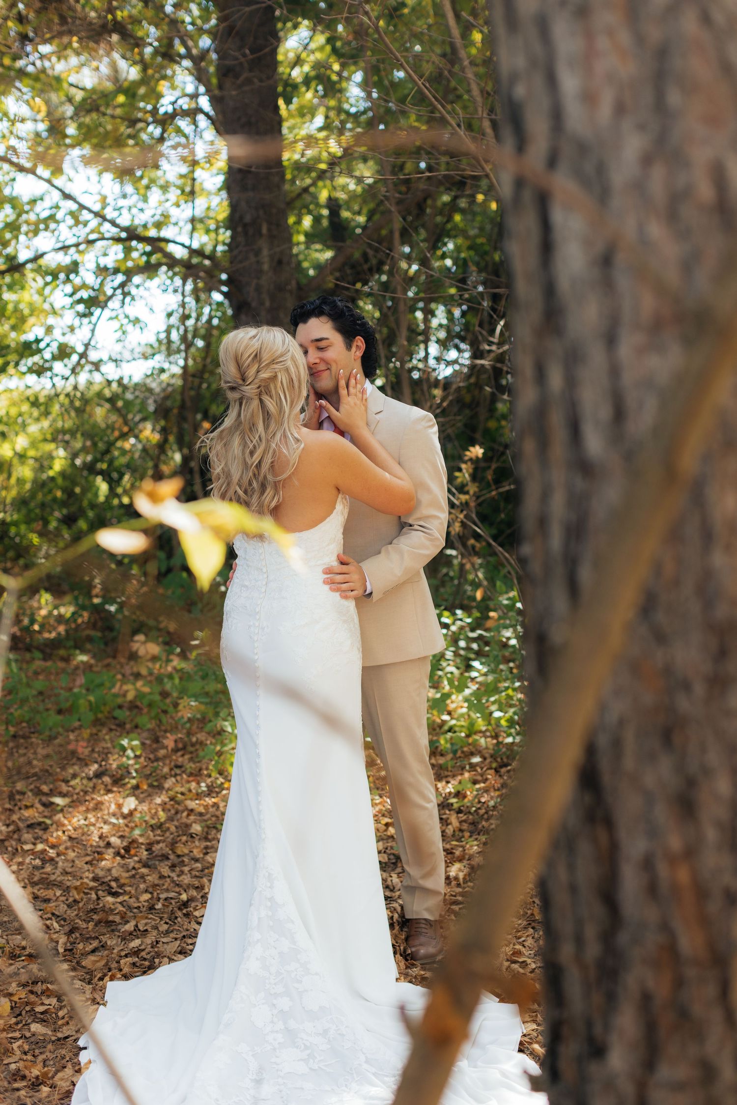Emotional first look sequence between newlyweds in a sunlit wooded area.