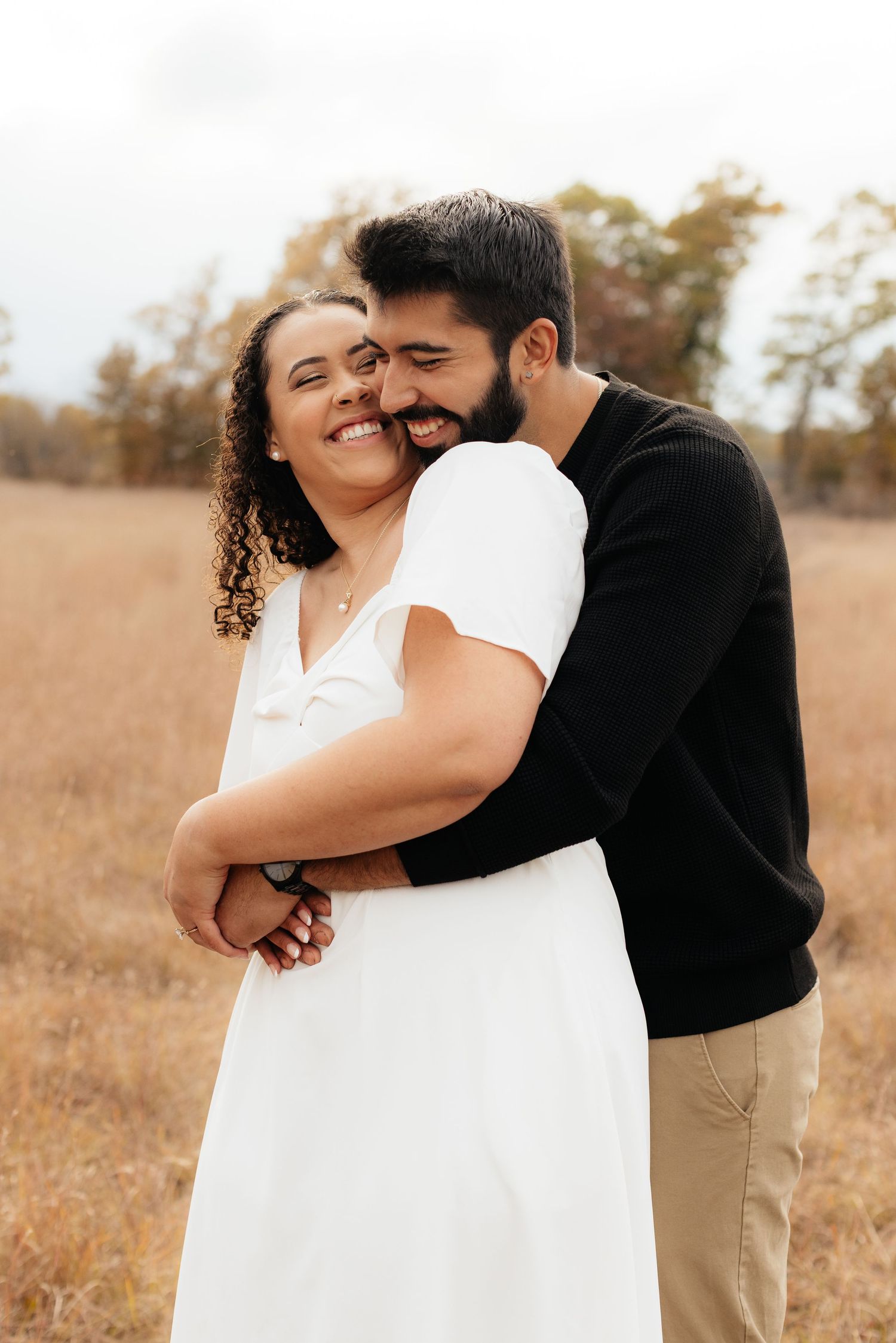 Romantic couple embraces in a golden field during sunset photoshoot.