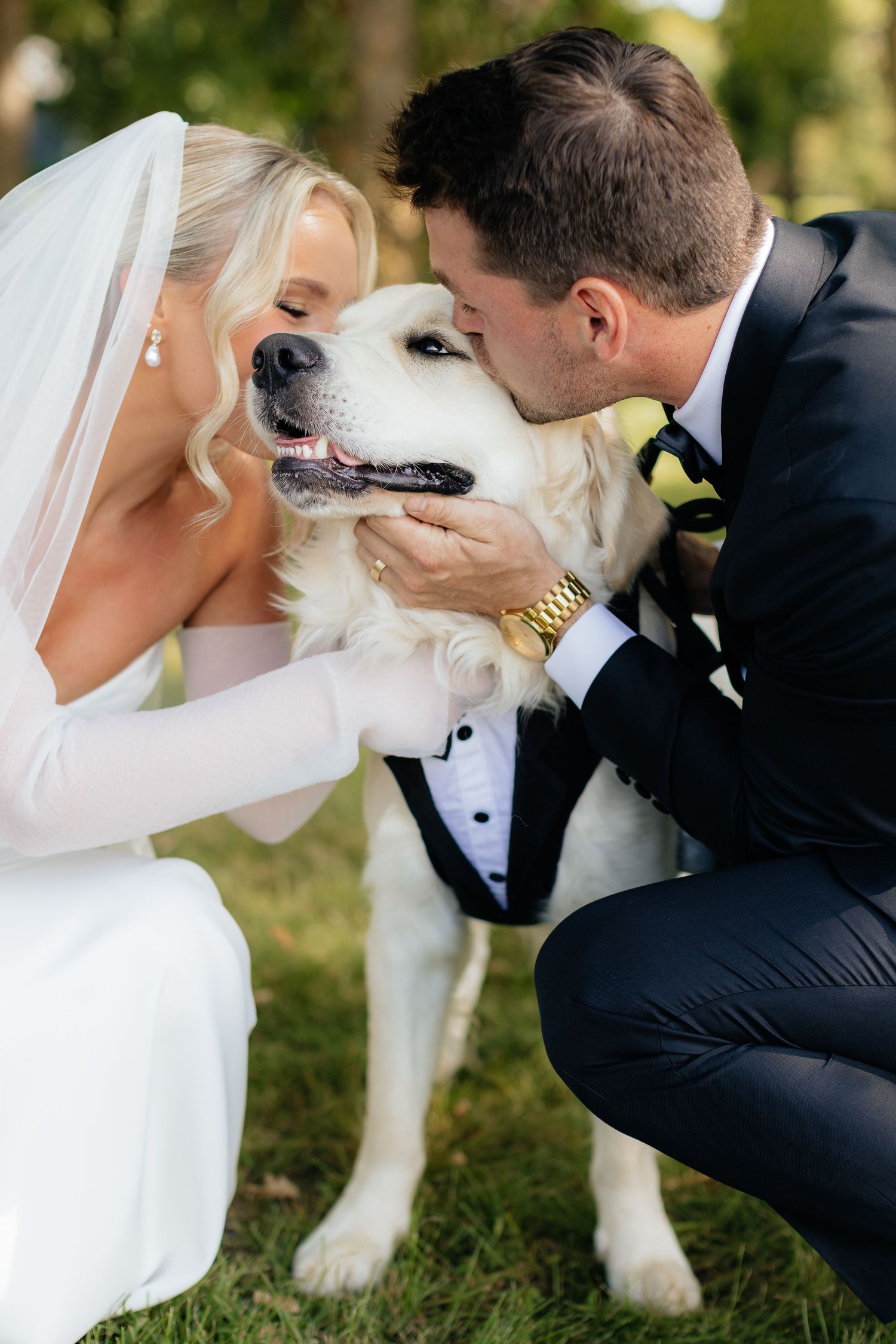Wedding couple shares a sweet moment with their dressed-up dog during photos.