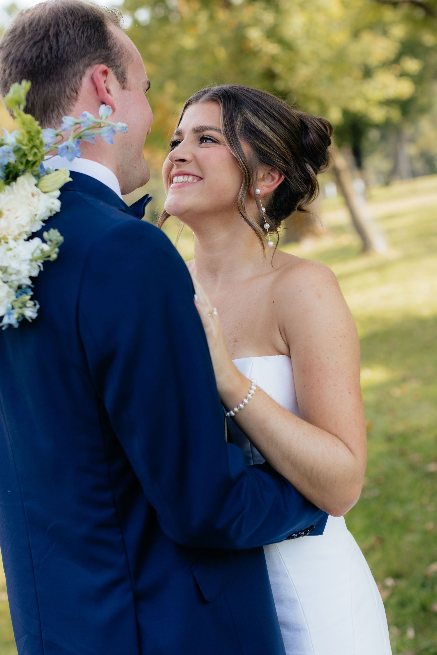 Joyful wedding couple embraces during outdoor portrait session.