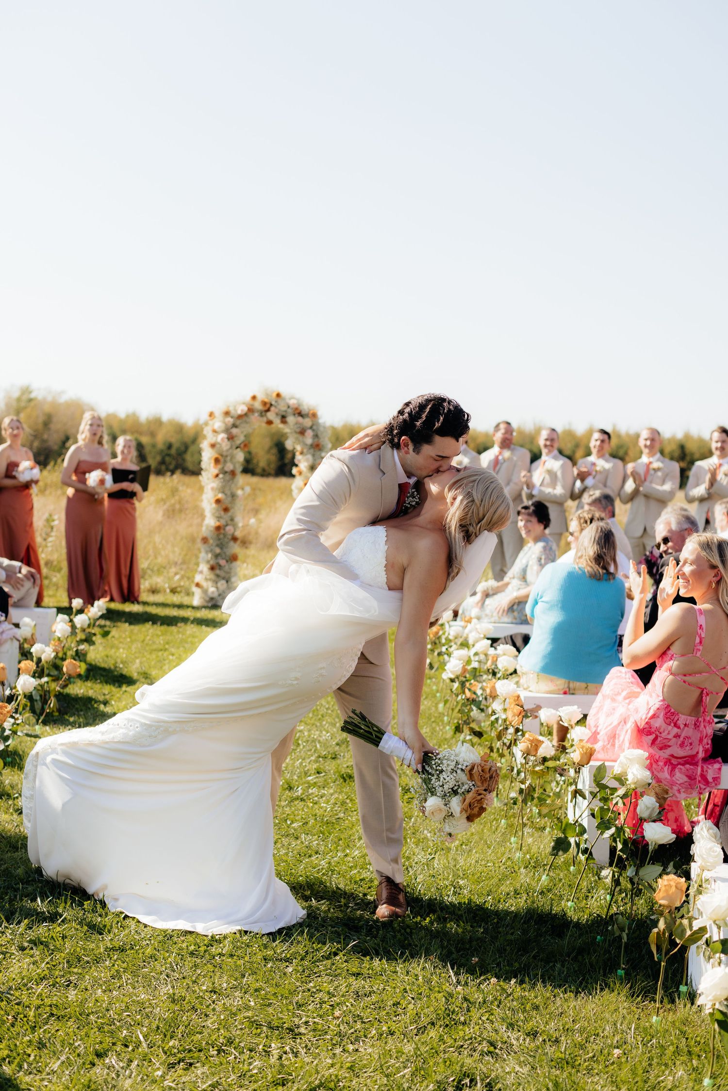 Wedding couple performs a choreographed dance sequence in a sunny outdoor field.