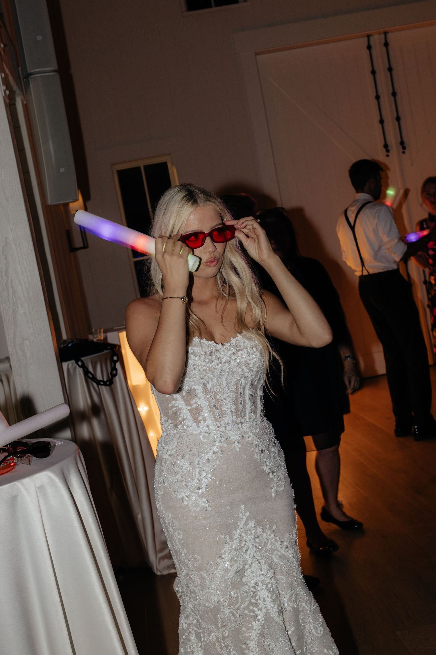 Wedding reception guests dancing with glow sticks and LED lights on a dark dance floor.