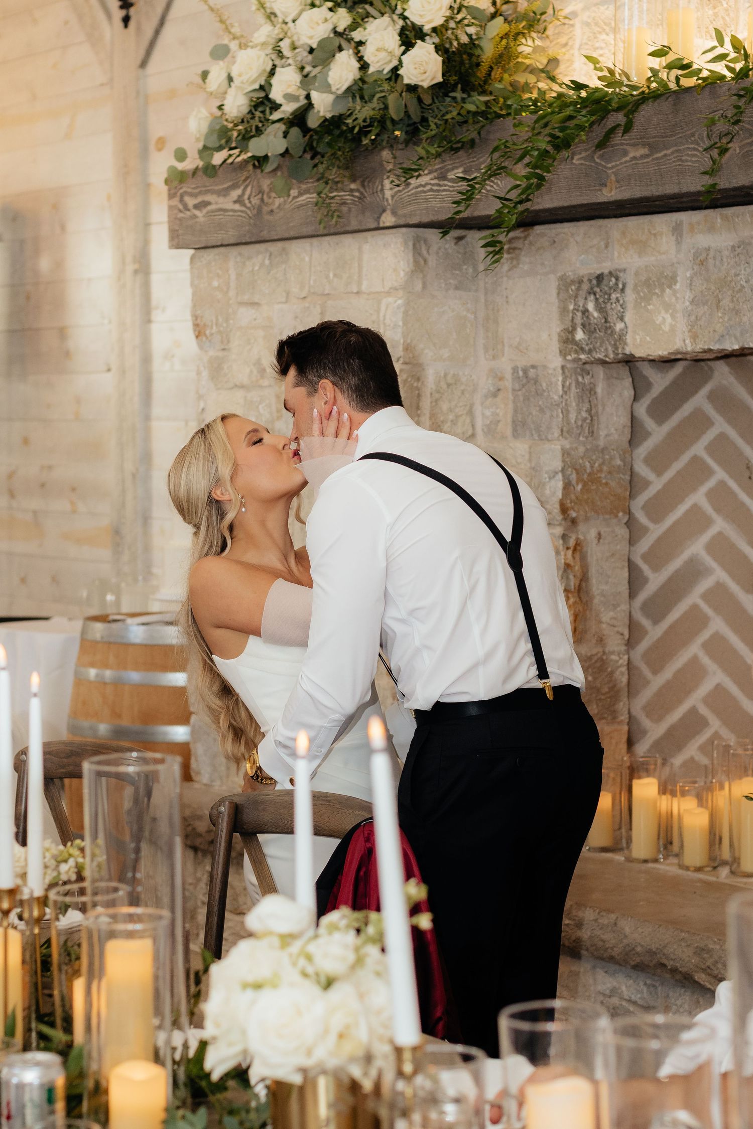 A romantic moment between newlyweds at their reception with white floral decorations and candlelight.