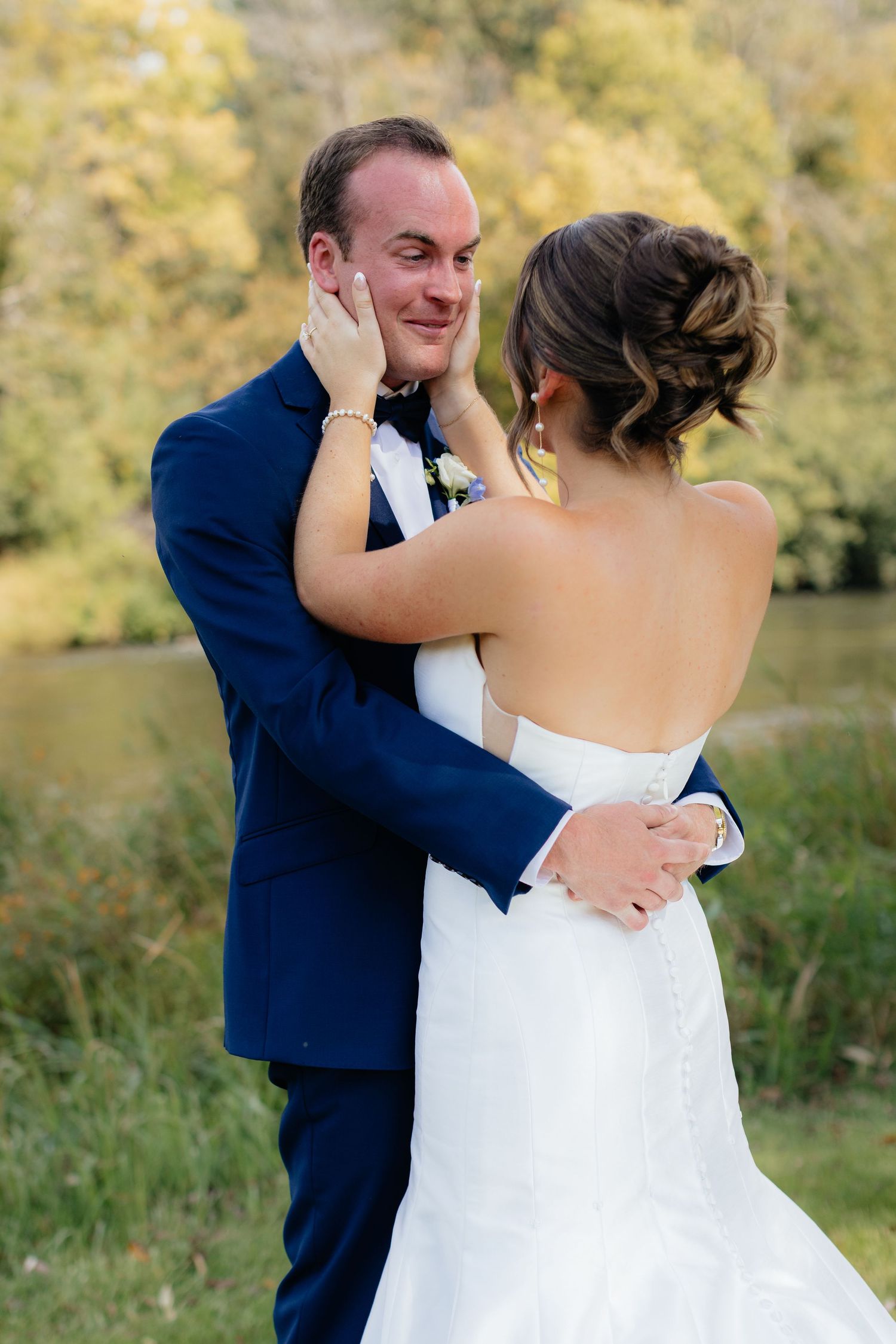 An emotional first look moment between newlyweds in an outdoor setting.