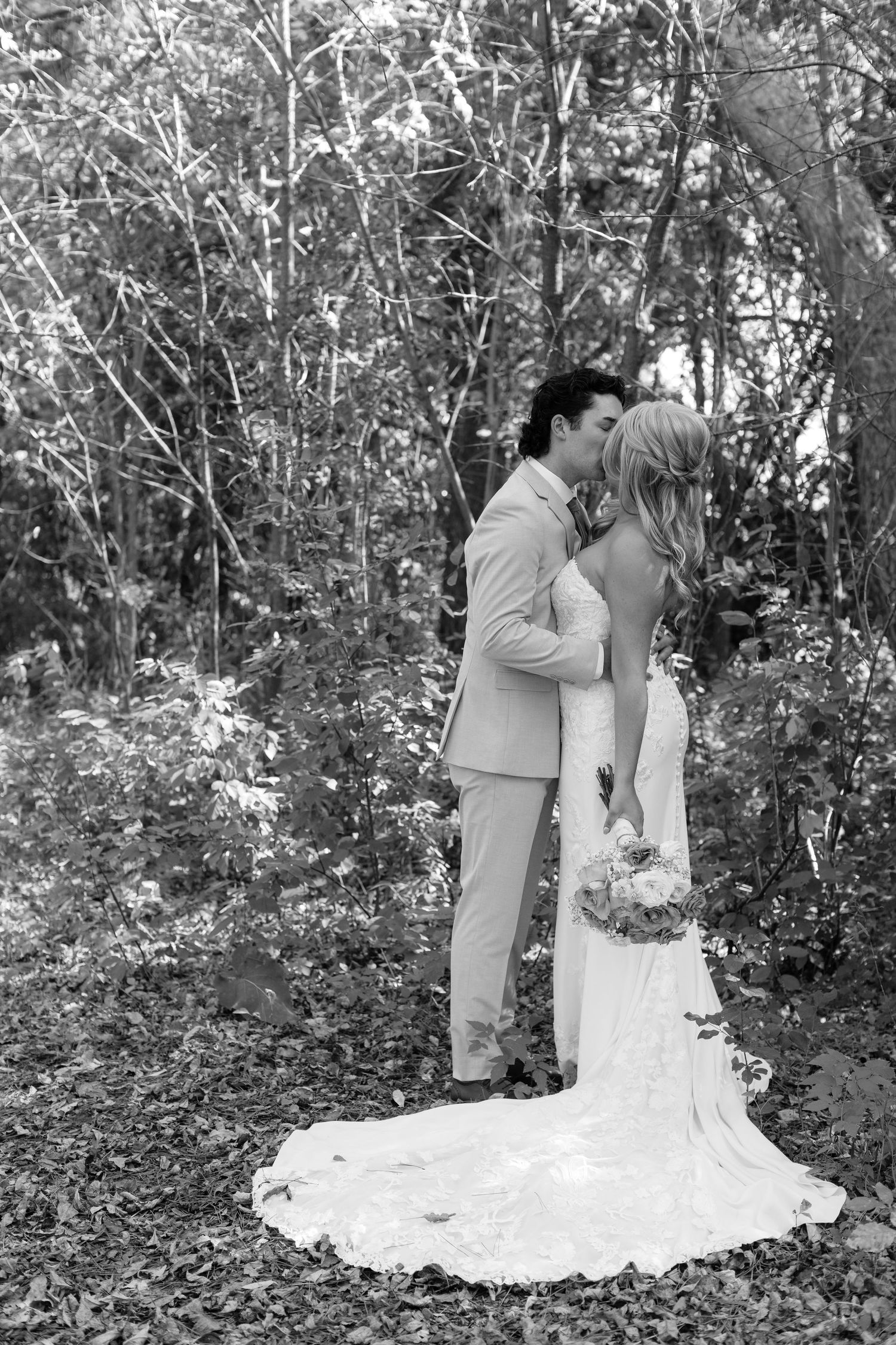 Black and white wedding photos showing tender moments between newlyweds in a natural setting.
