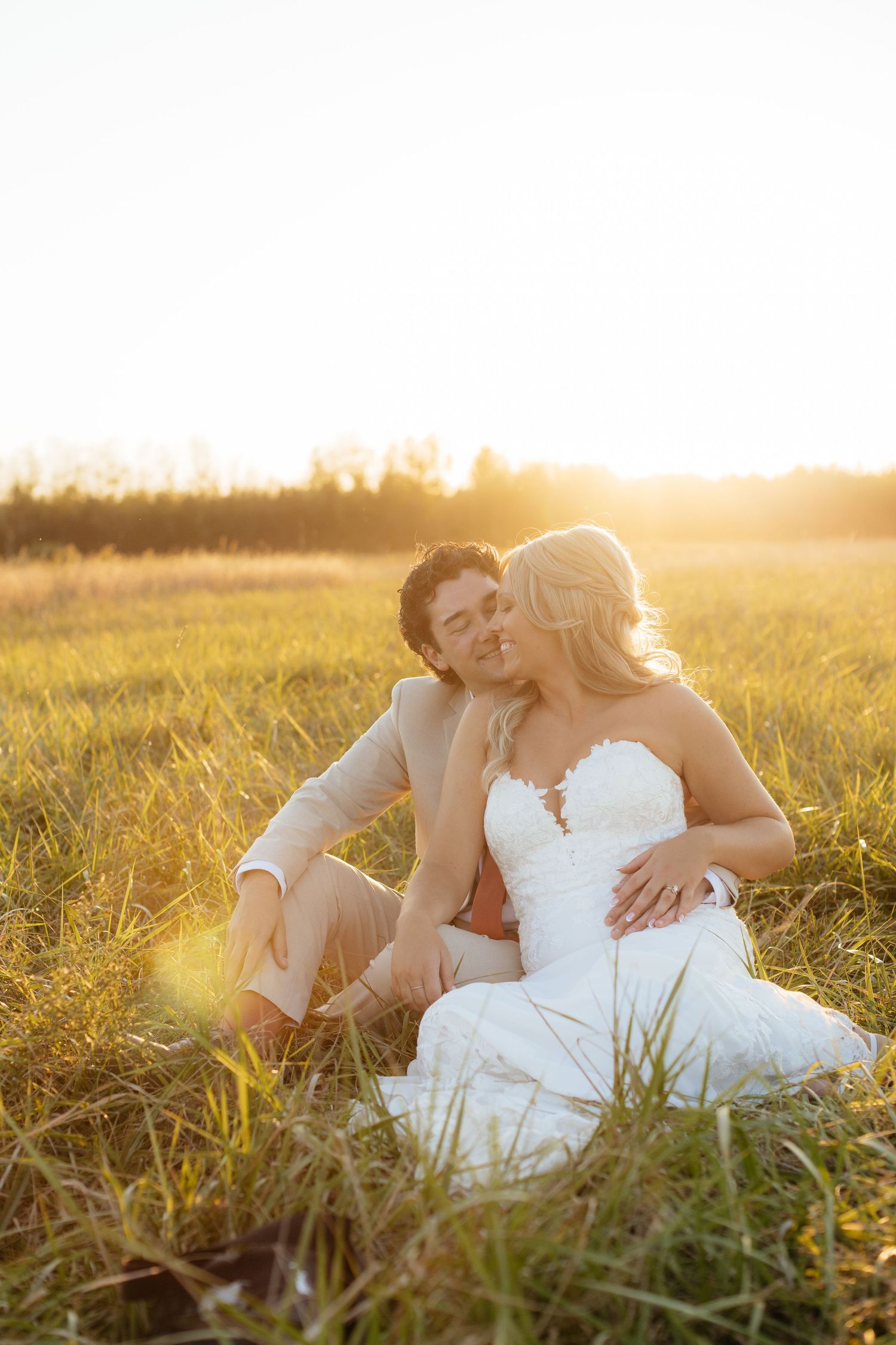 Intimate wedding portraits of couple laying in grass during golden hour.