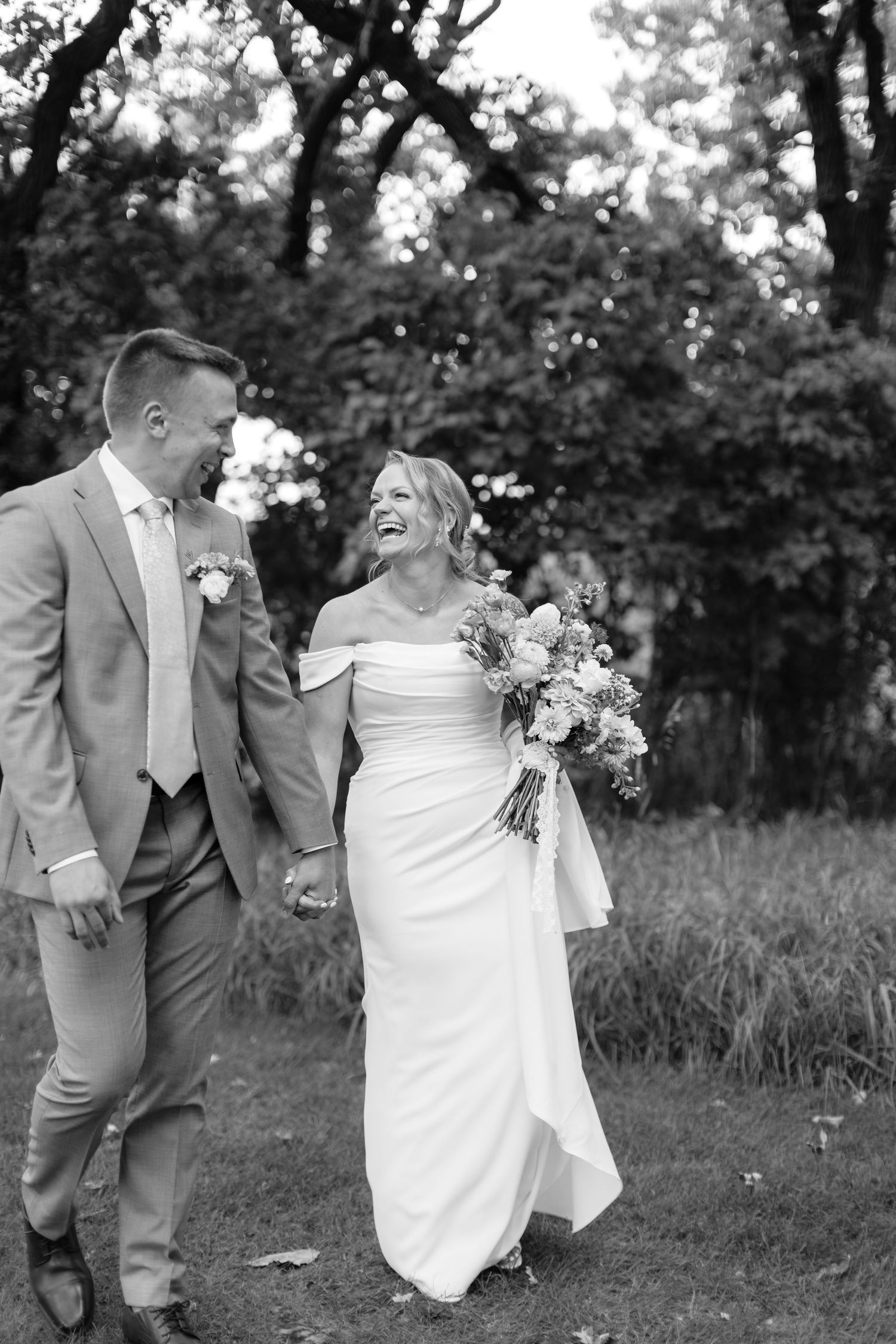Black and white photo of a couple laughing together in a garden setting.