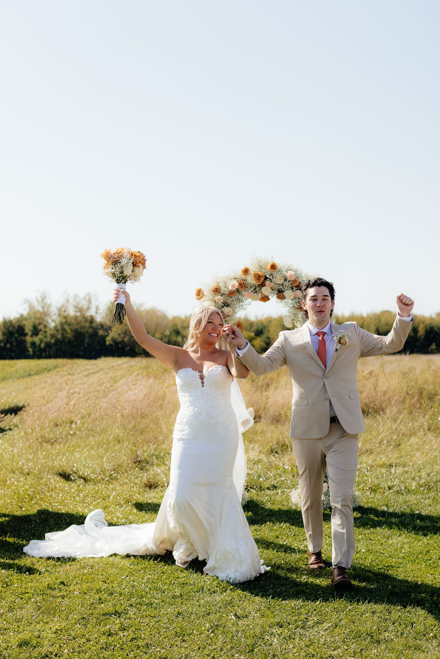 Newlyweds dance and celebrate together in an outdoor field setting.