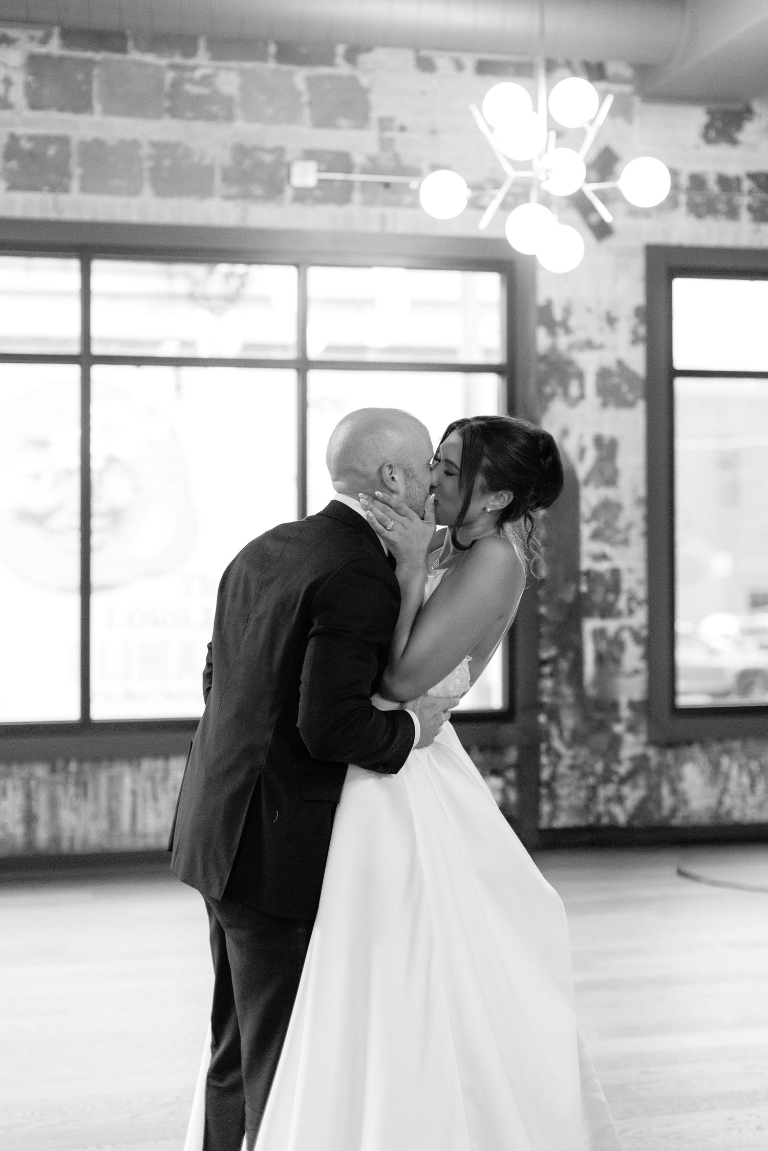 A black and white photo captures an intimate dance moment in an industrial-style venue.
