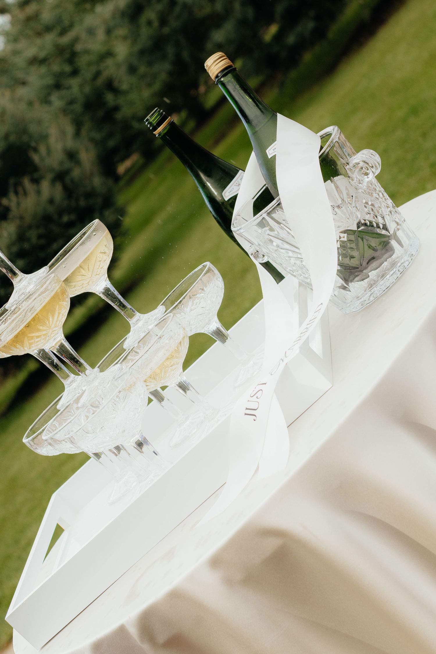 Elegant champagne glasses with white lace decorations arranged on a table at a wedding reception.