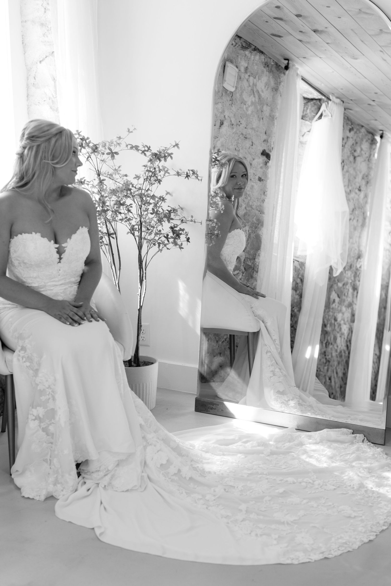 Elegant white wedding dress with lace details and long train displayed in a bright interior setting.