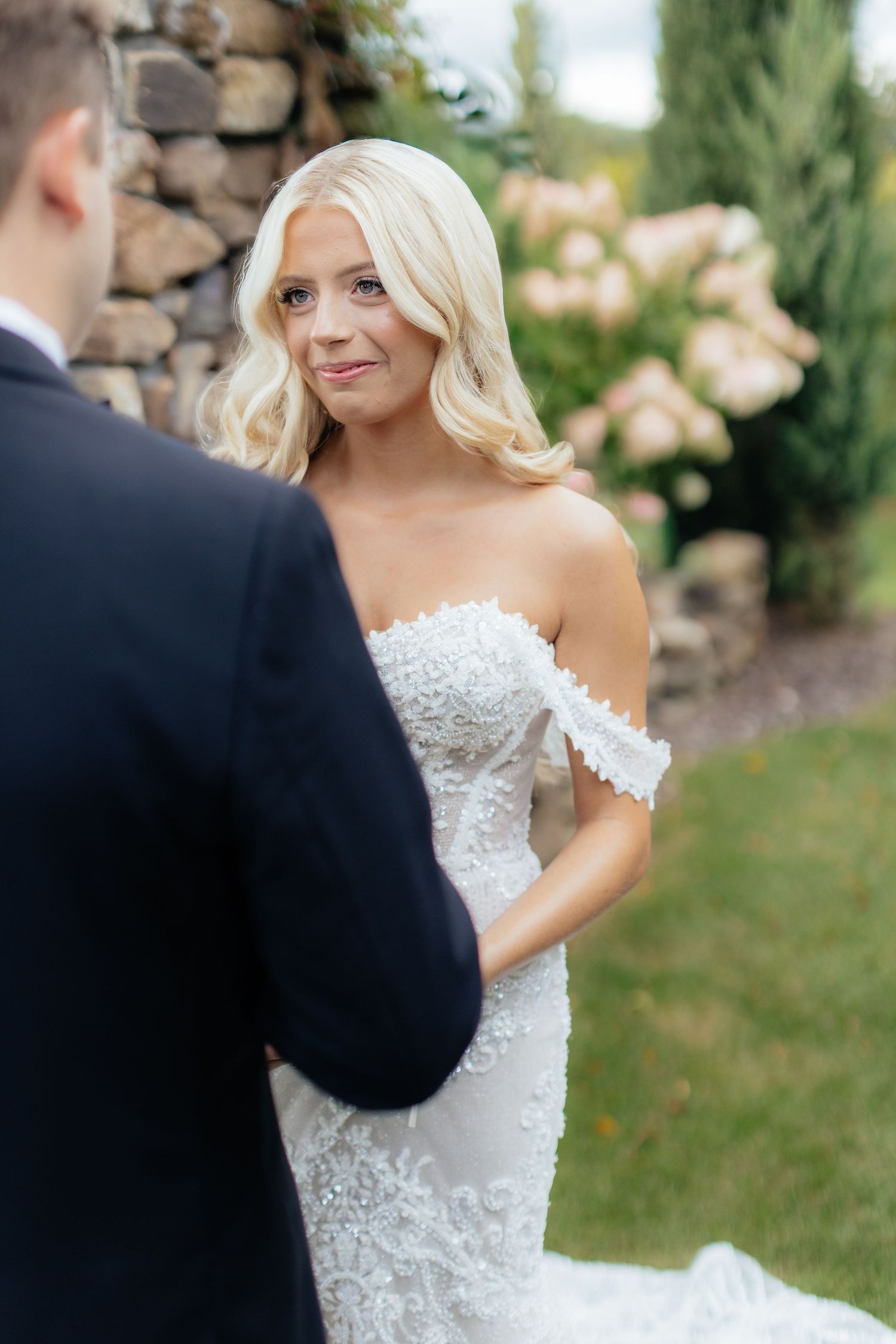 An intimate moment captured during a wedding ceremony against a stone wall backdrop.