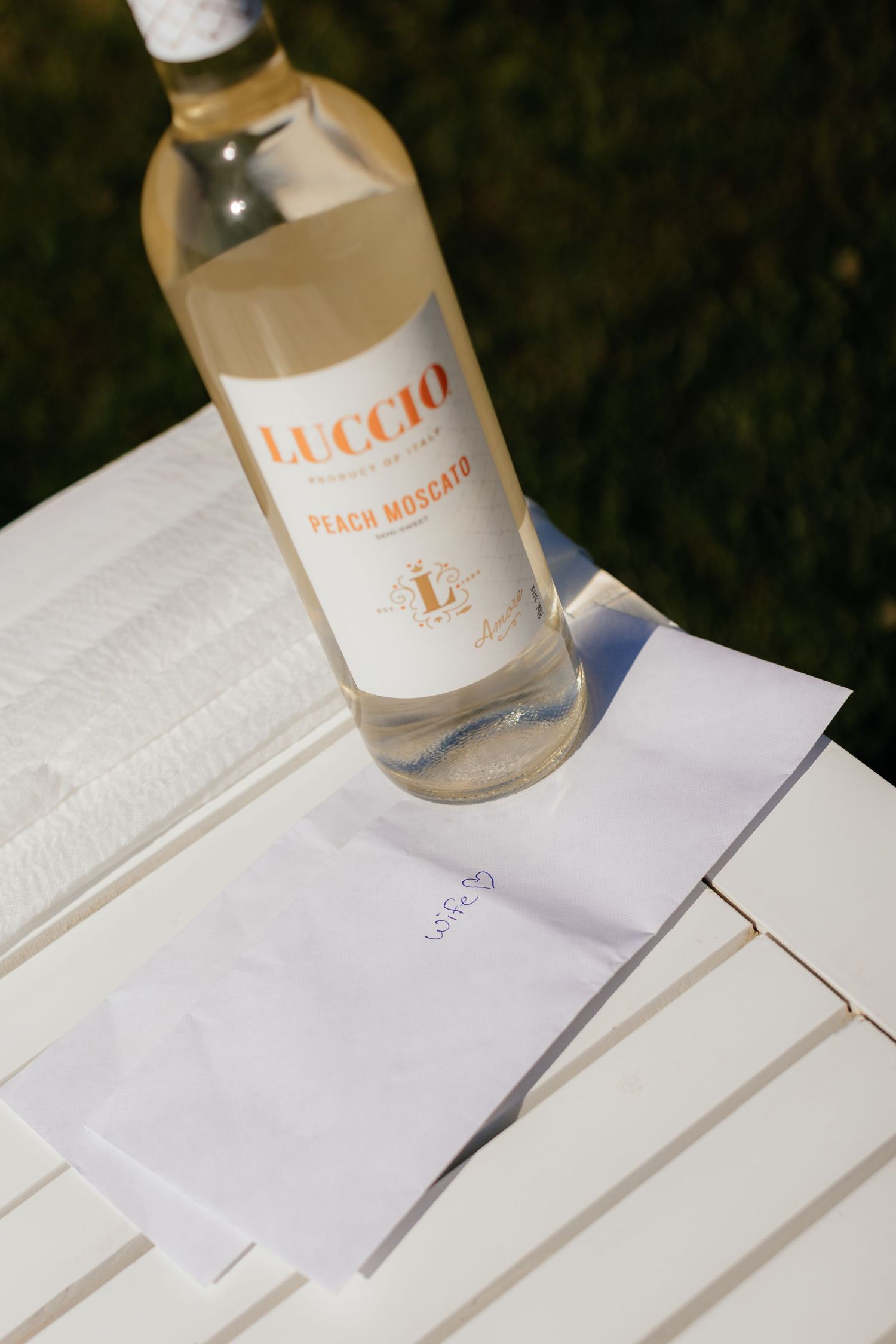 Wedding detail shot of wine bottles on white surface.