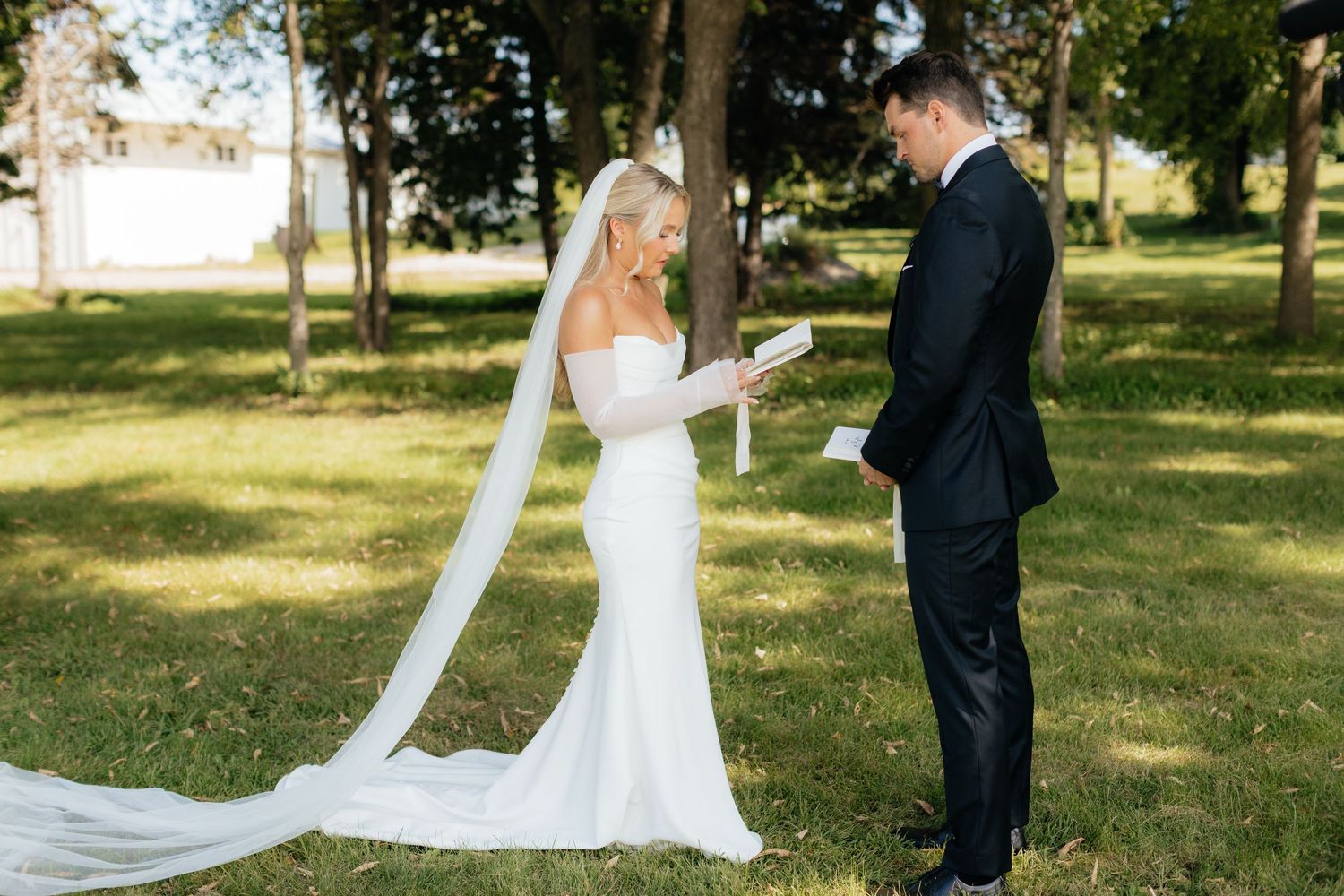 Wedding couple poses elegantly in a sun-dappled garden setting.