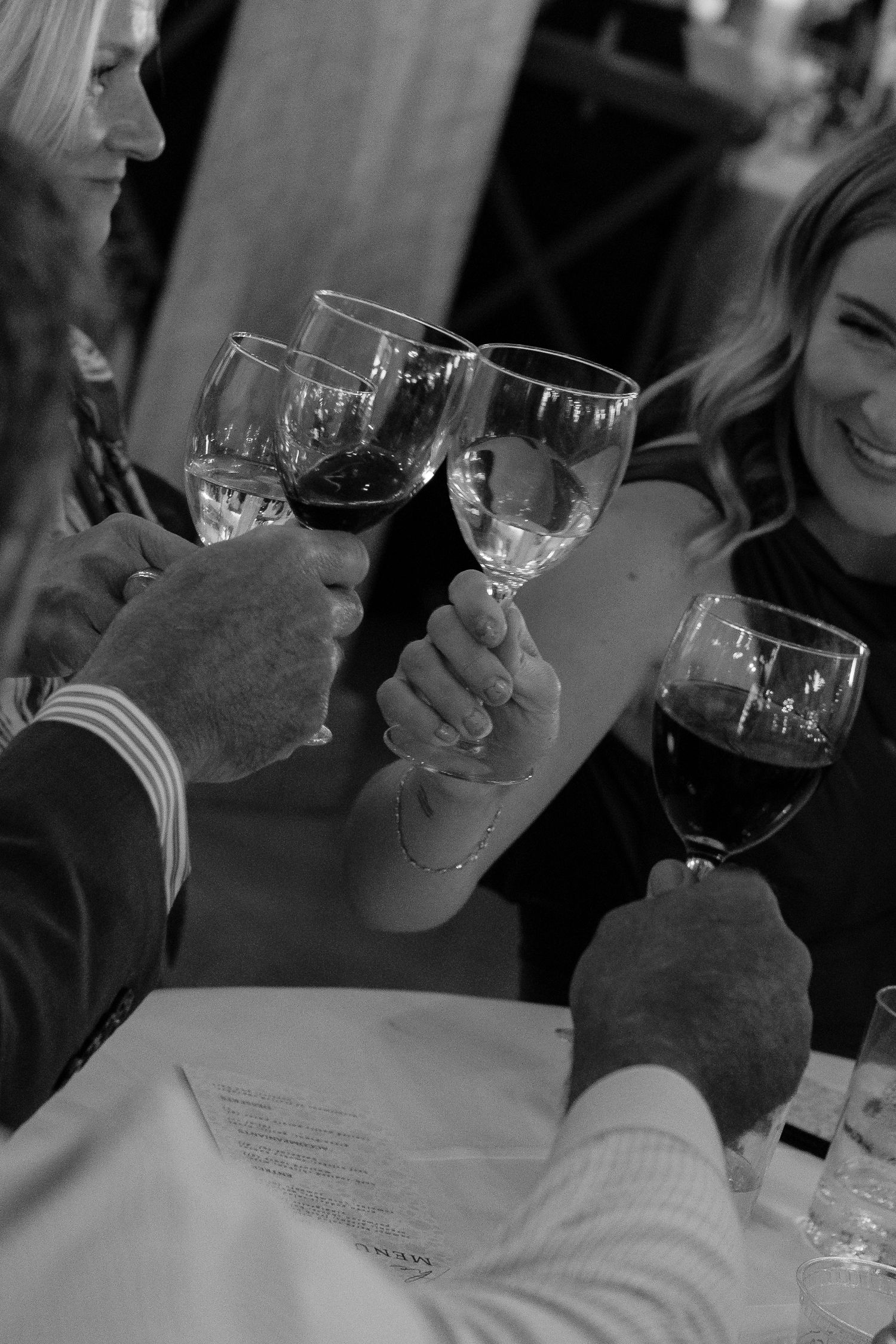 Wedding guests raising wine glasses in a celebratory toast at the reception.