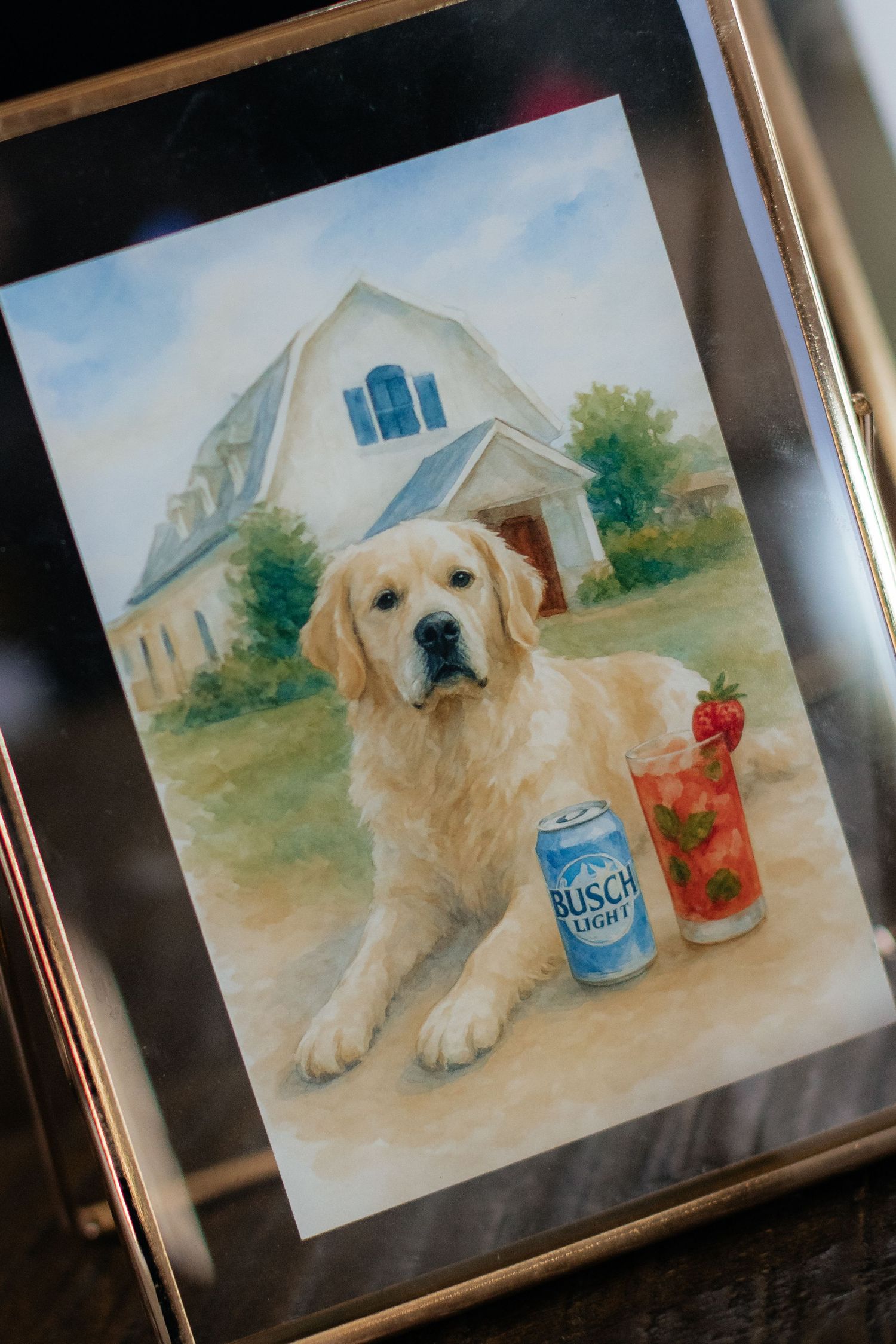 Framed watercolor painting of a golden retriever with summer drinks on a porch.