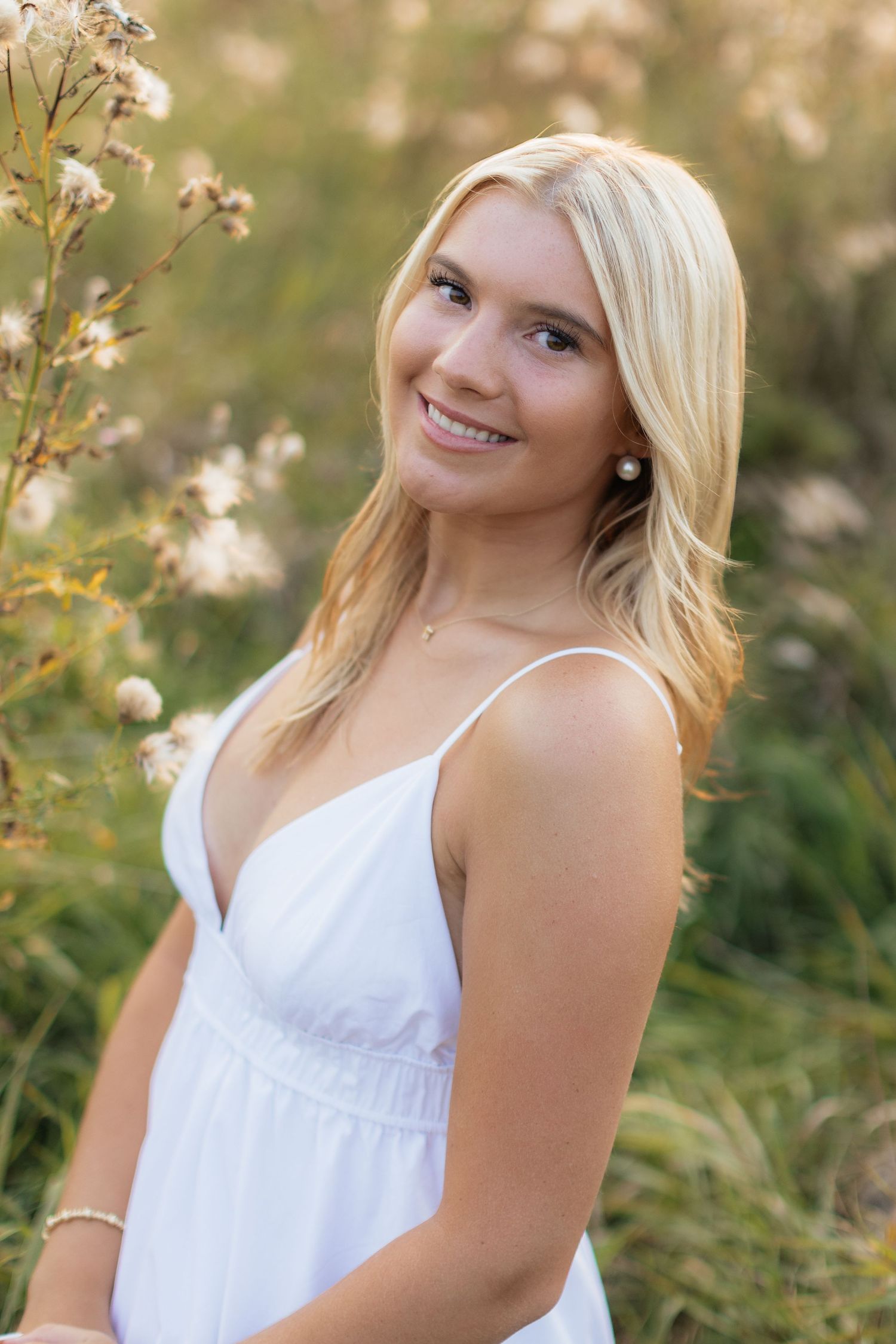 Summer portrait session in white dress among wildflowers at sunset.