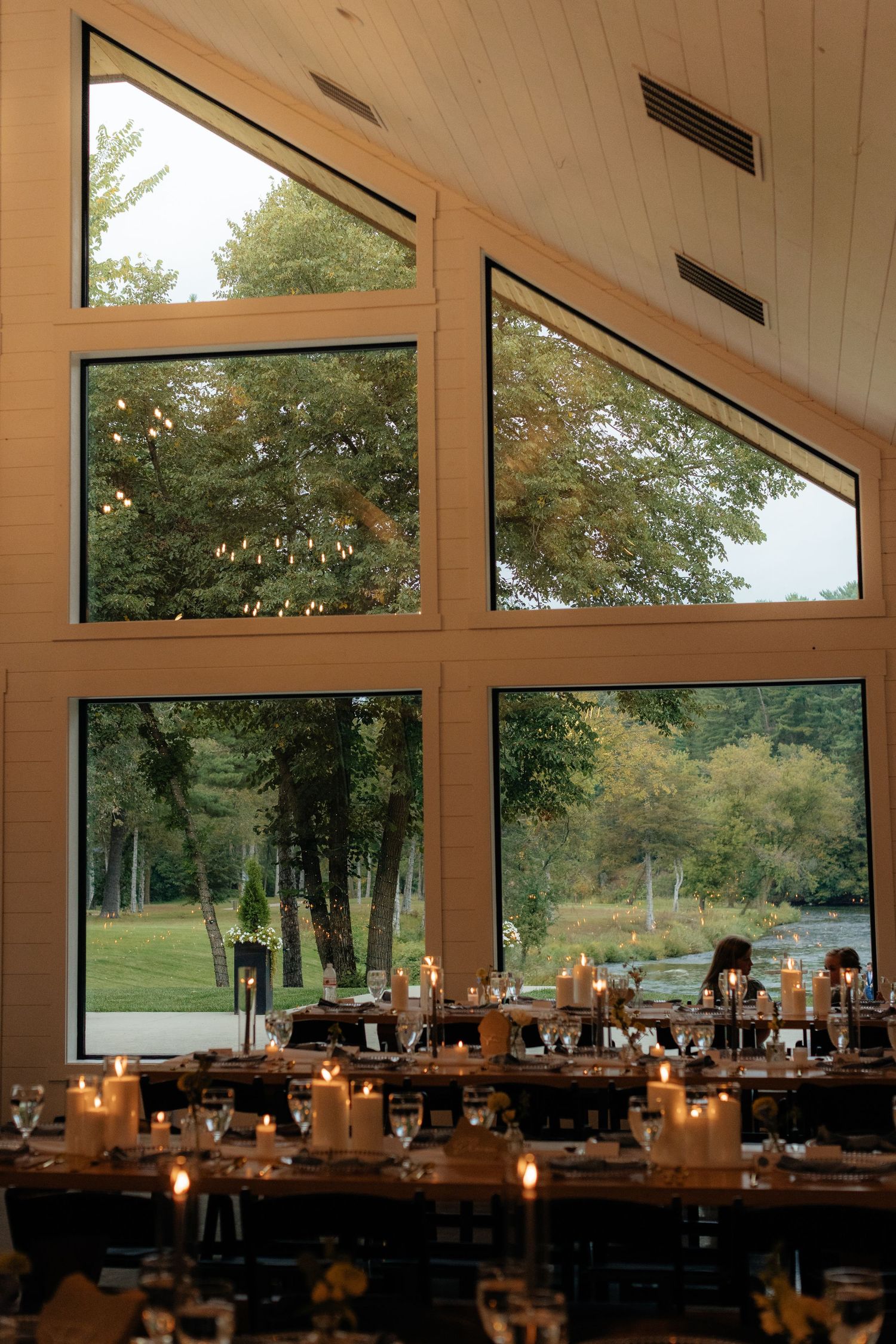 Modern wedding venue interior with vaulted ceiling, large windows, and natural light.