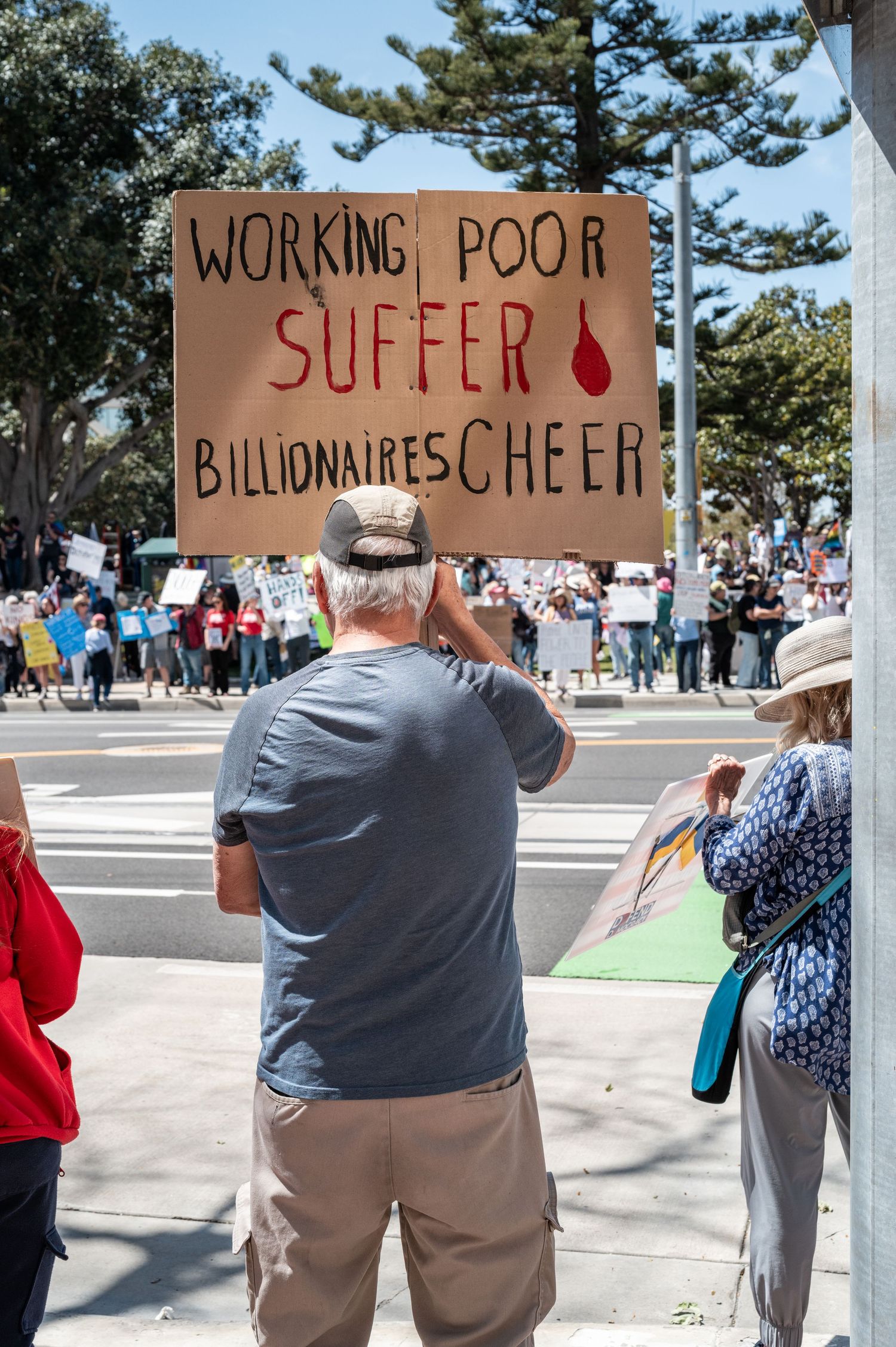 Protesters holding handmade cardboard signs at outdoor rally.