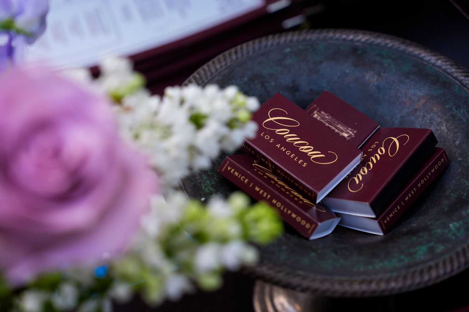 Elegant Cacao de Chocolat luxury chocolate boxes displayed on a decorative tray with pink roses at a wedding.