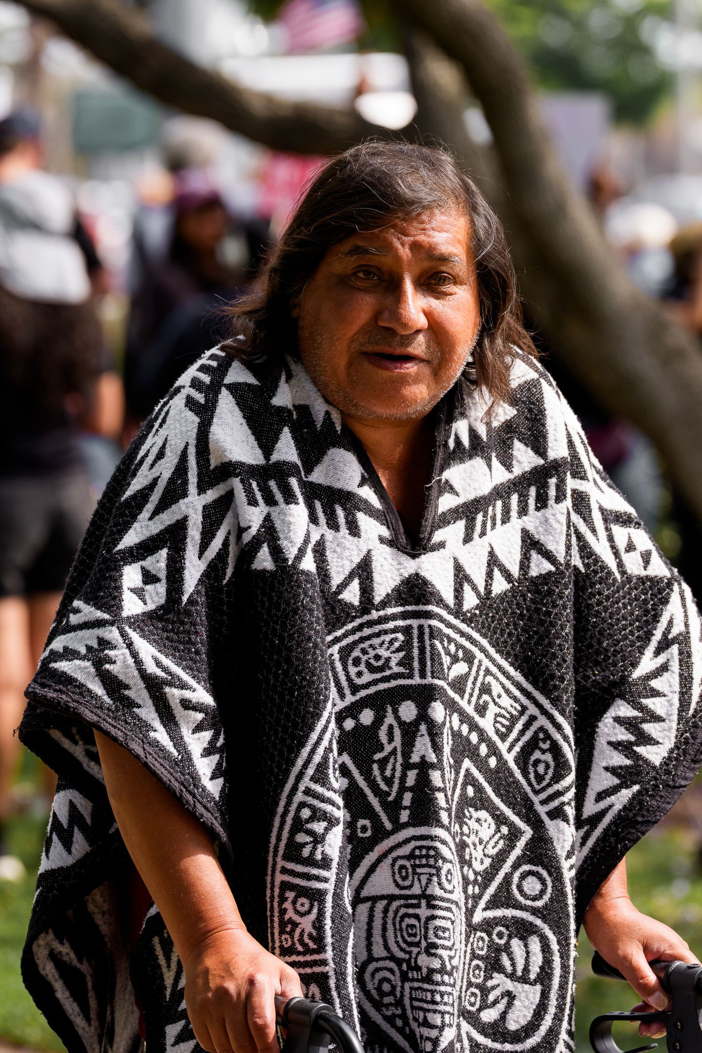 Person wearing a black and white patterned poncho at an outdoor gathering.