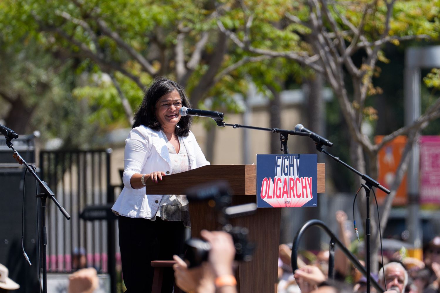 Campaign rally scene with podium and signs in outdoor setting.