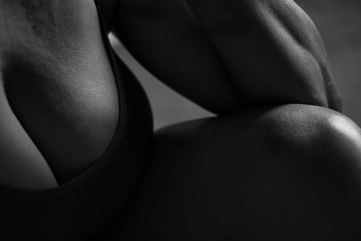 Black and white close-up of toned athletic body muscles in dramatic studio lighting.