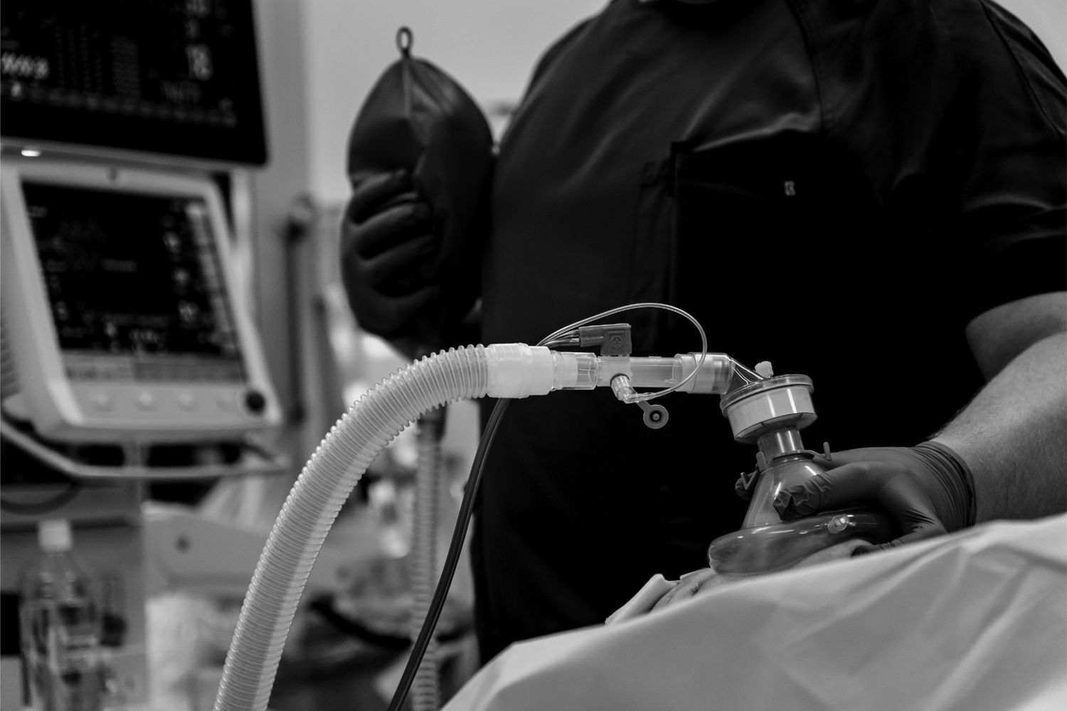 Black and white image of an anesthesiologist administering anesthesia with breathing mask to a patient pre-surgery.