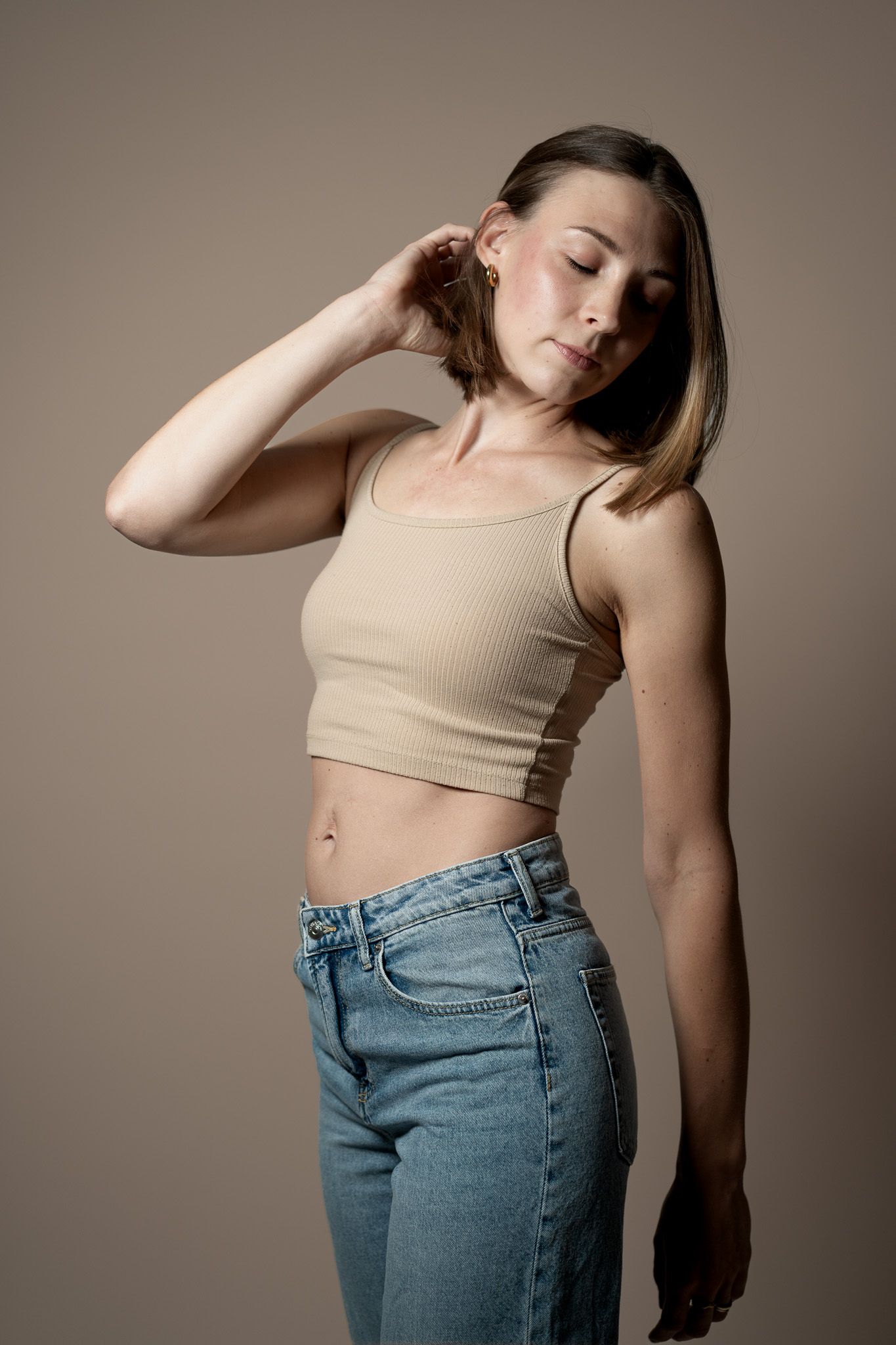 Ein Beauty-Portrait von einer jungen Frau die sich leicht nach hinten streckt und sich dabei durch die Haare fährt.