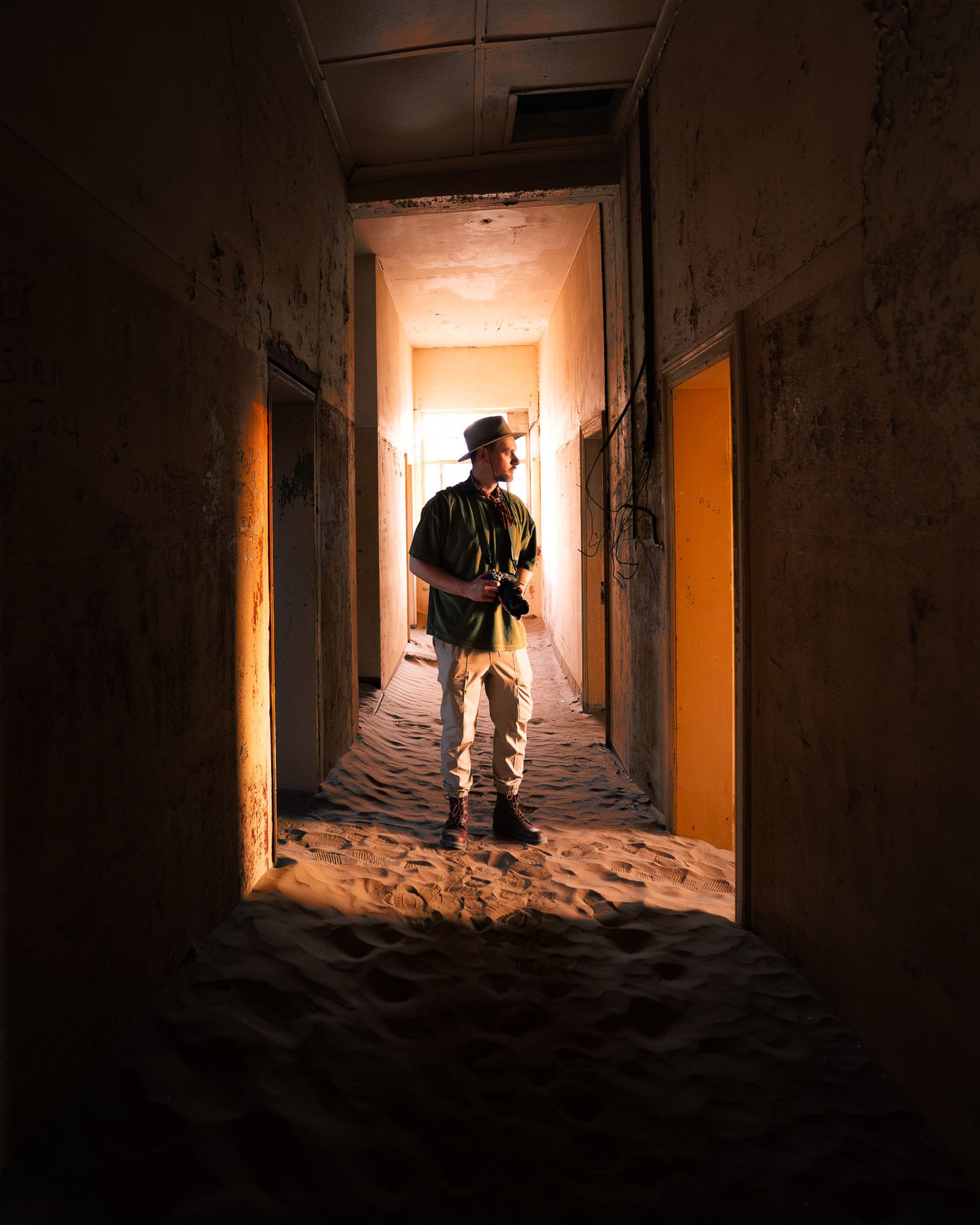 Ein Abenteurer in einem vom Wüstensand zurückeroberten Gebäude in Kolmanskop, Namibia. Spiel mit Licht und Schatten.