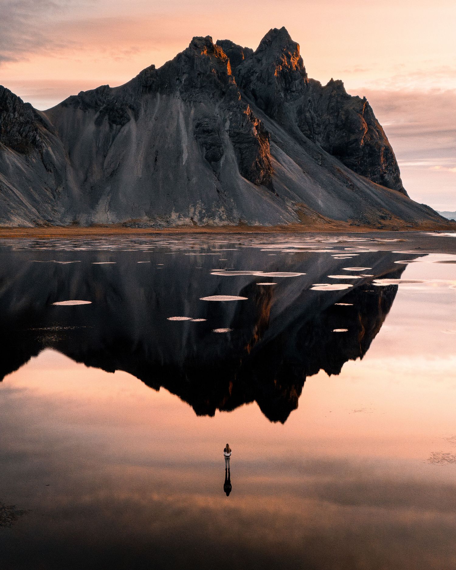 Eine gigantische Landschaftsaufnahme von Stokksnes, Island mit Blick auf das Vestrahorn, das vom Sonnenaufgang eingefärbt wird.