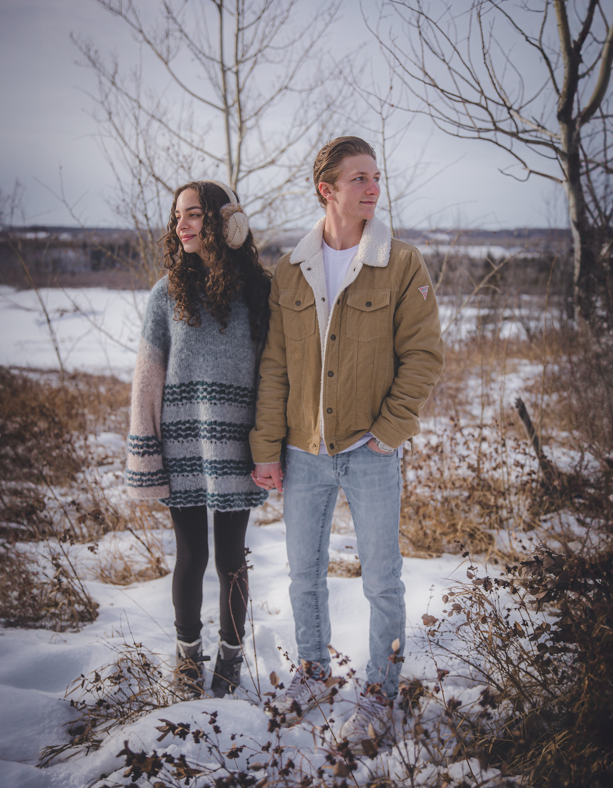 Couple holding hands in the snow looking in opposite directions