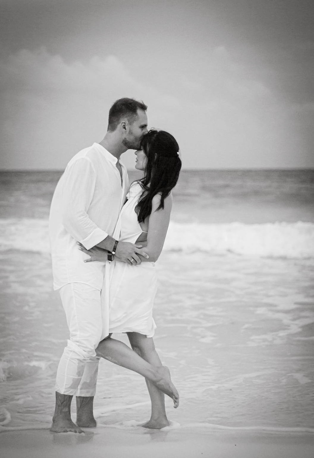 Man kissing womens forehead while they embrace