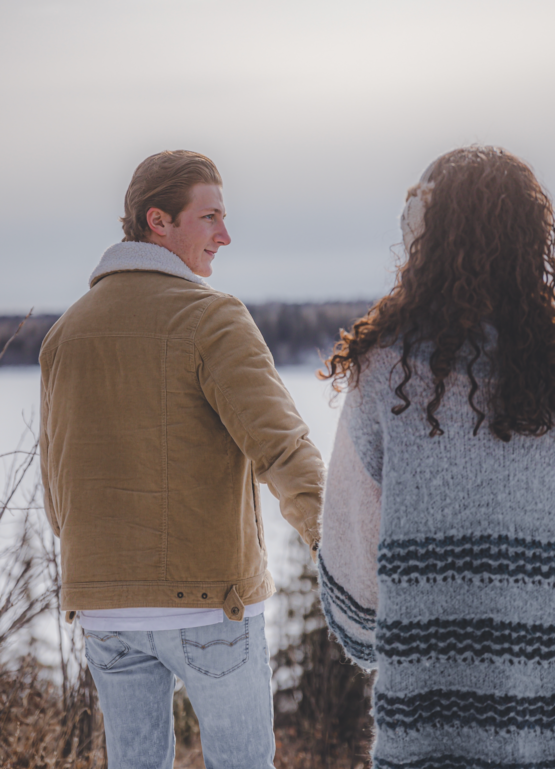 Man holding womens hand leading her while looking away smiling