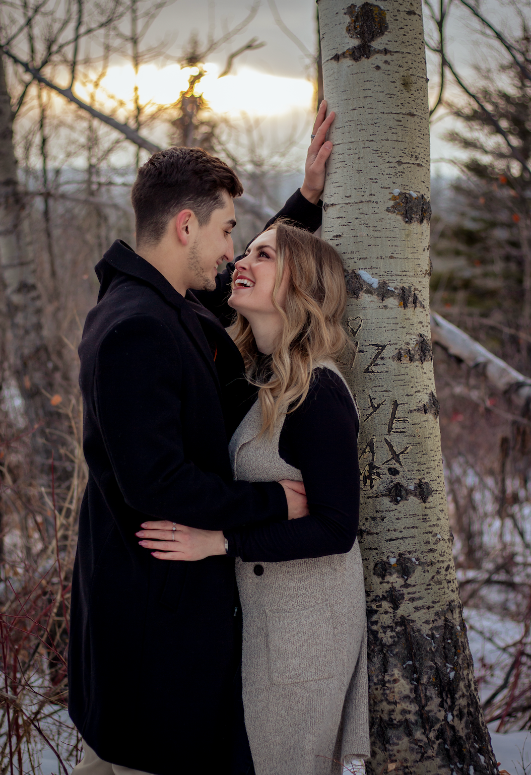 man and women smiling at eachother against a tree