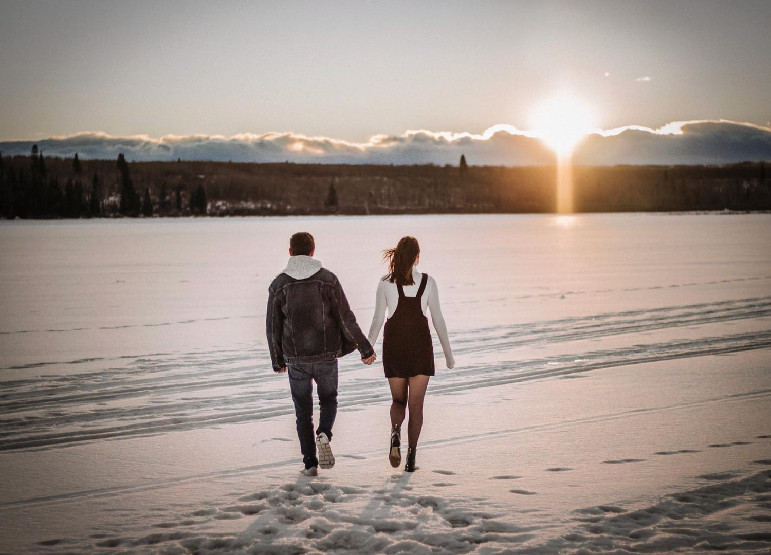 Couple walking into the distance in the snow during sunset