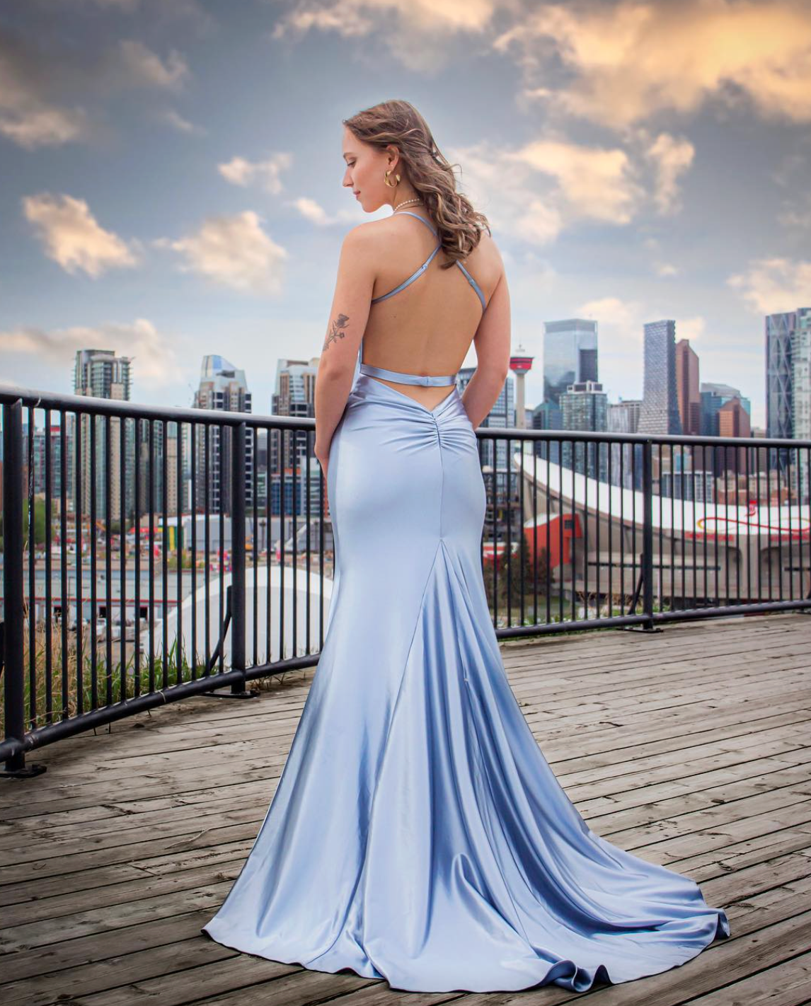 girl in blue dress posing with her back to the camera by the calgary downtown skyline