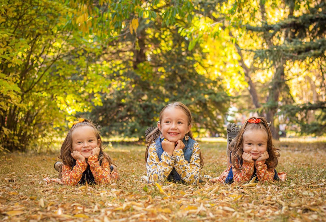 Three children laying on their tummy with hands under chin.