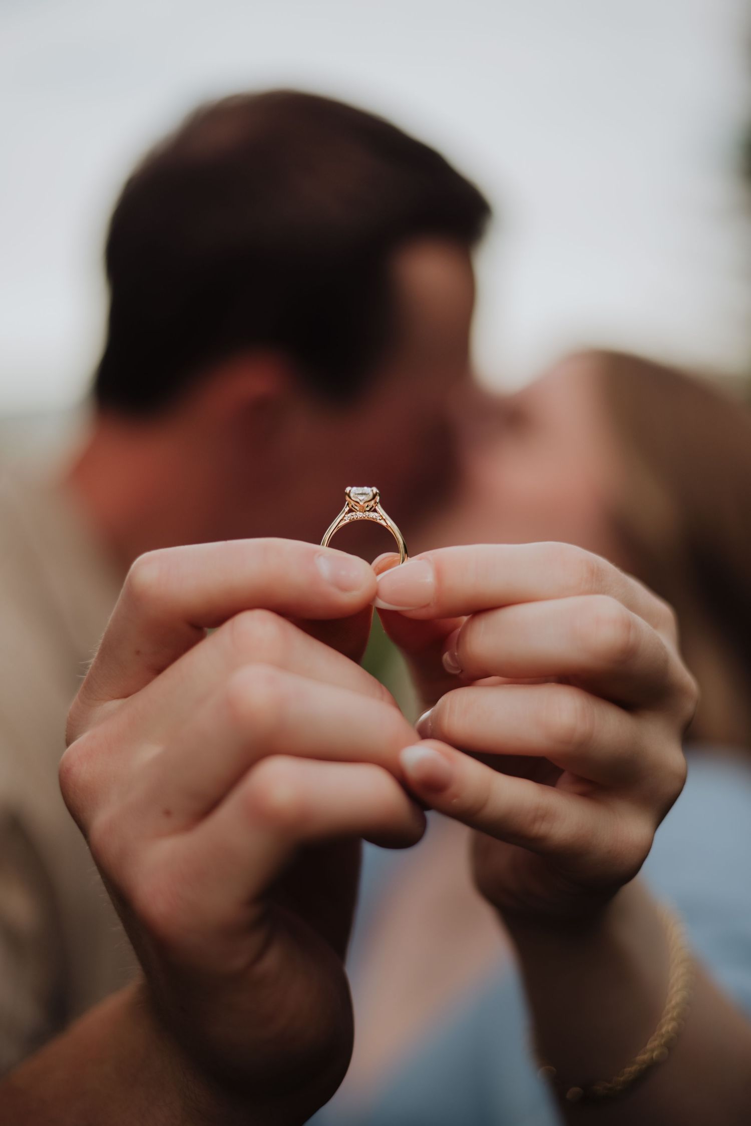 Close up of hands holding and presenting an engagement ring.